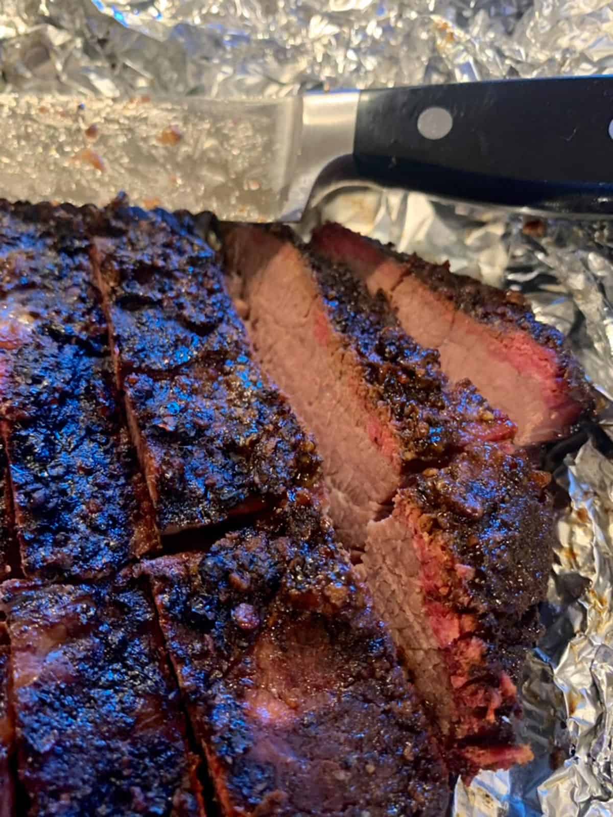 A smoked brisket that has been cut an a knife.