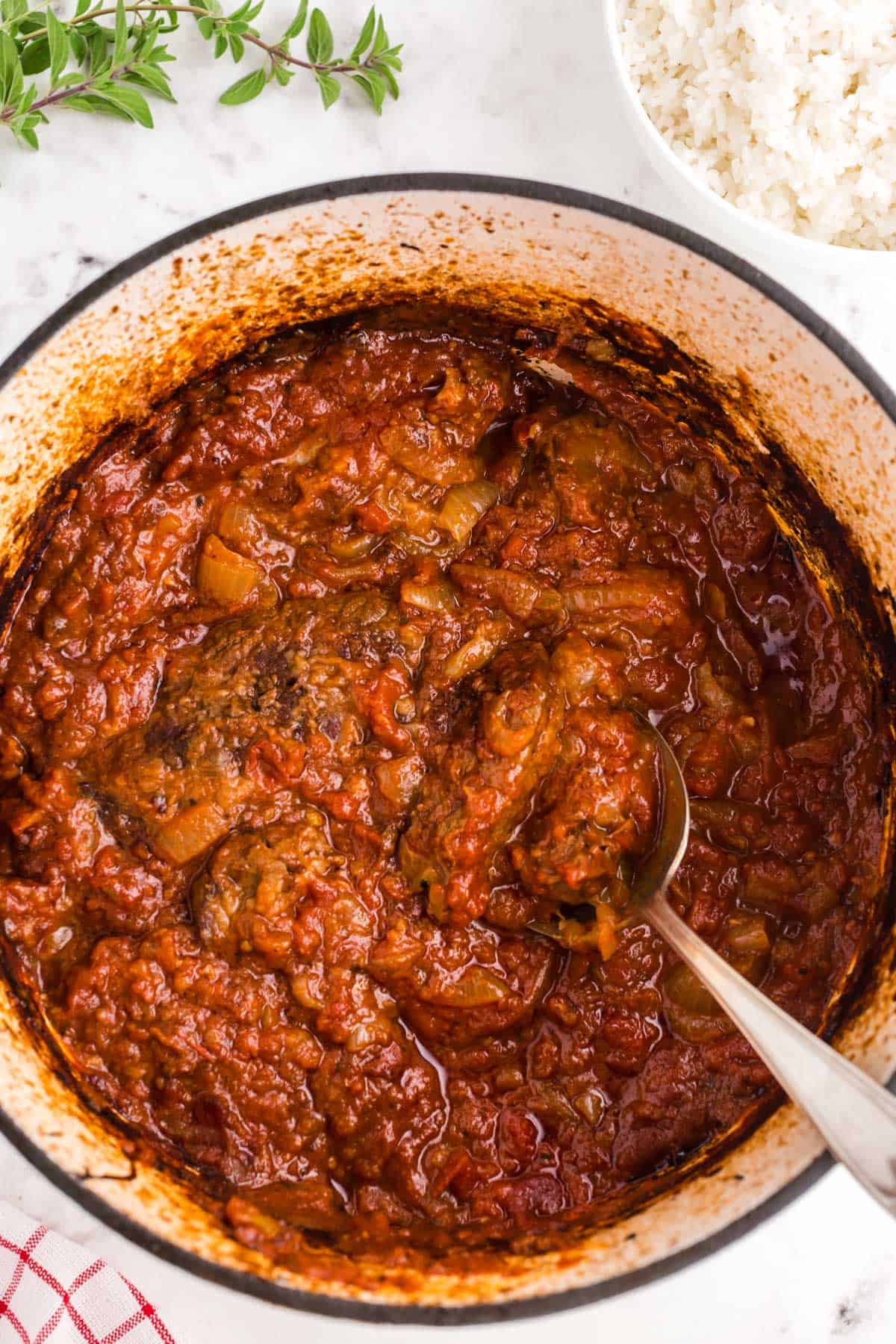 A Pot of Swiss steak with a spoon in it.