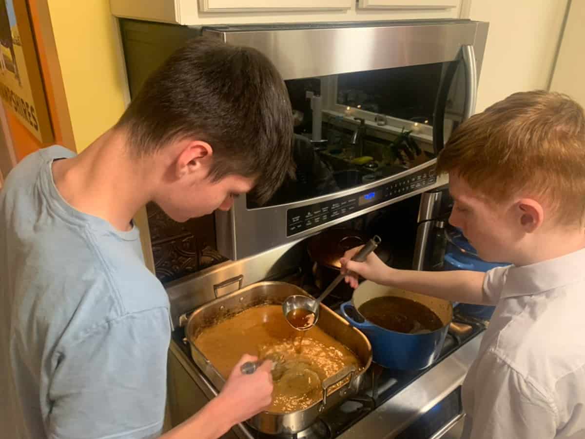 Two boys cooking over a stove.
