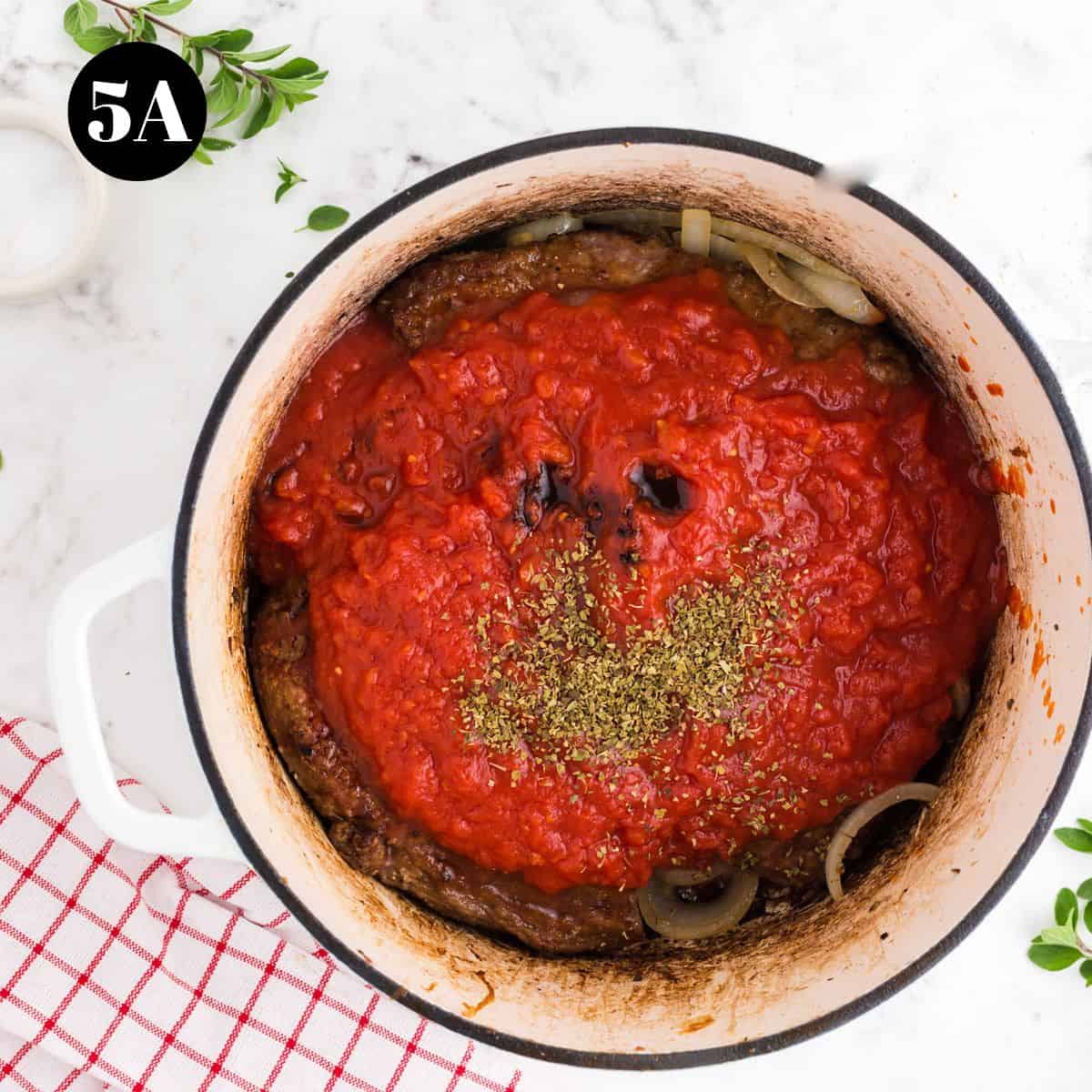 A pot of meat with tomato sauce and dried herbs.