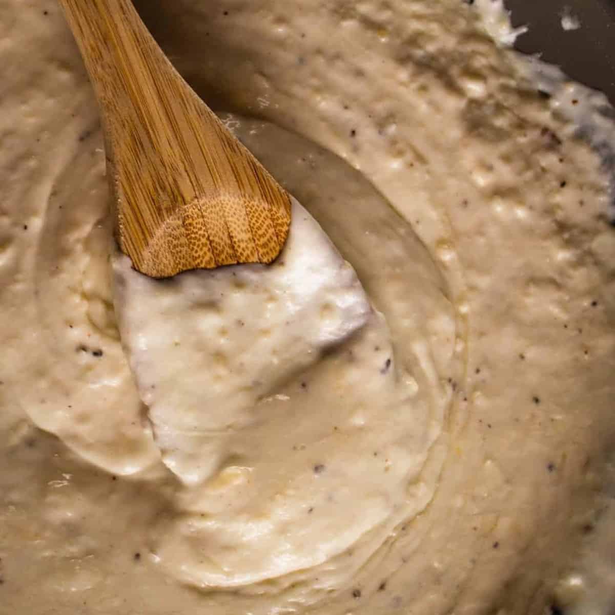 Stirring some alfredo sauce in a pan.