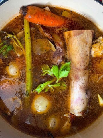 a pot of stock with a long bone in it.