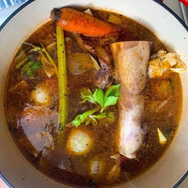 a pot of stock with a long bone in it.