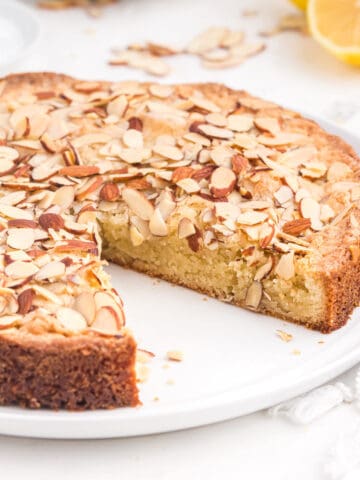 An almond cake with a slice missing.