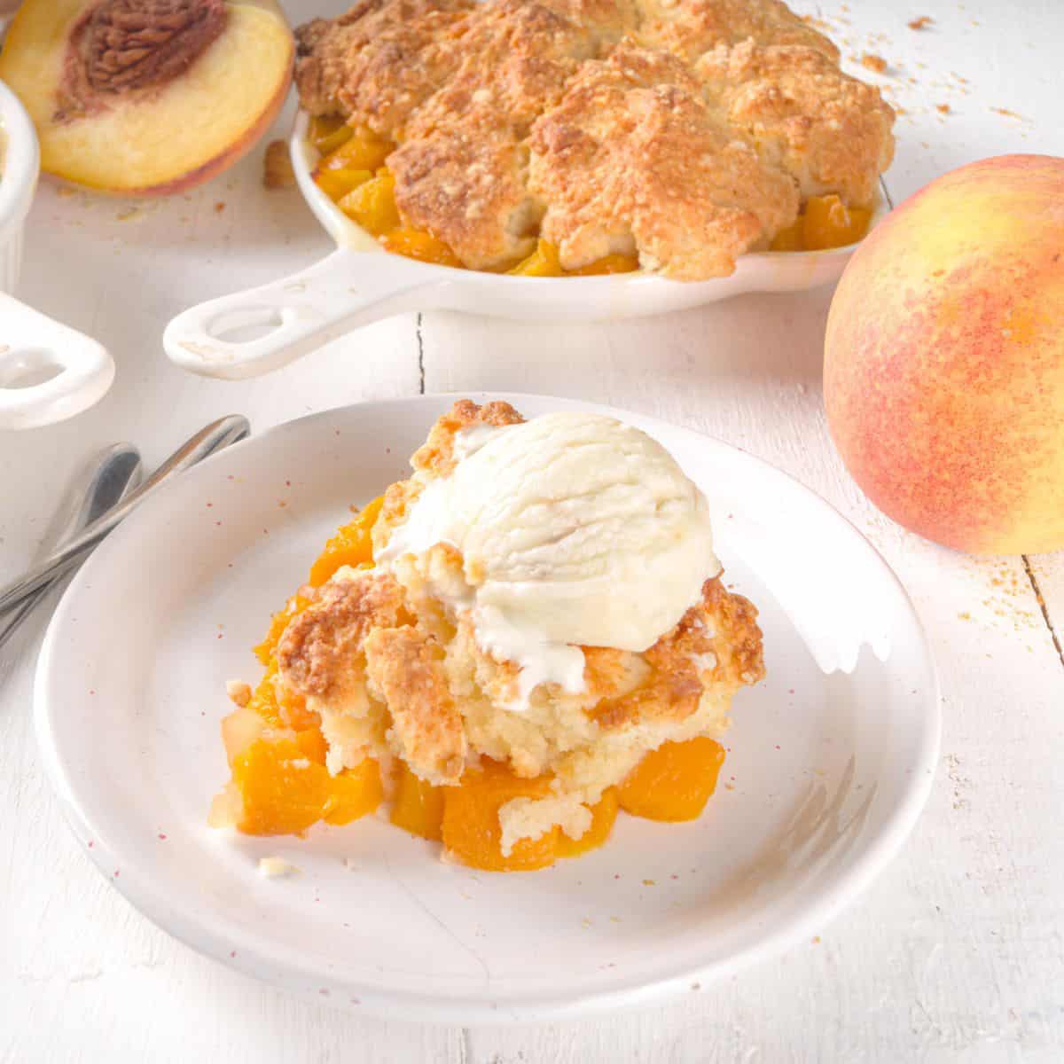 A plate of peach cobbler with vanilla ice cream on top.