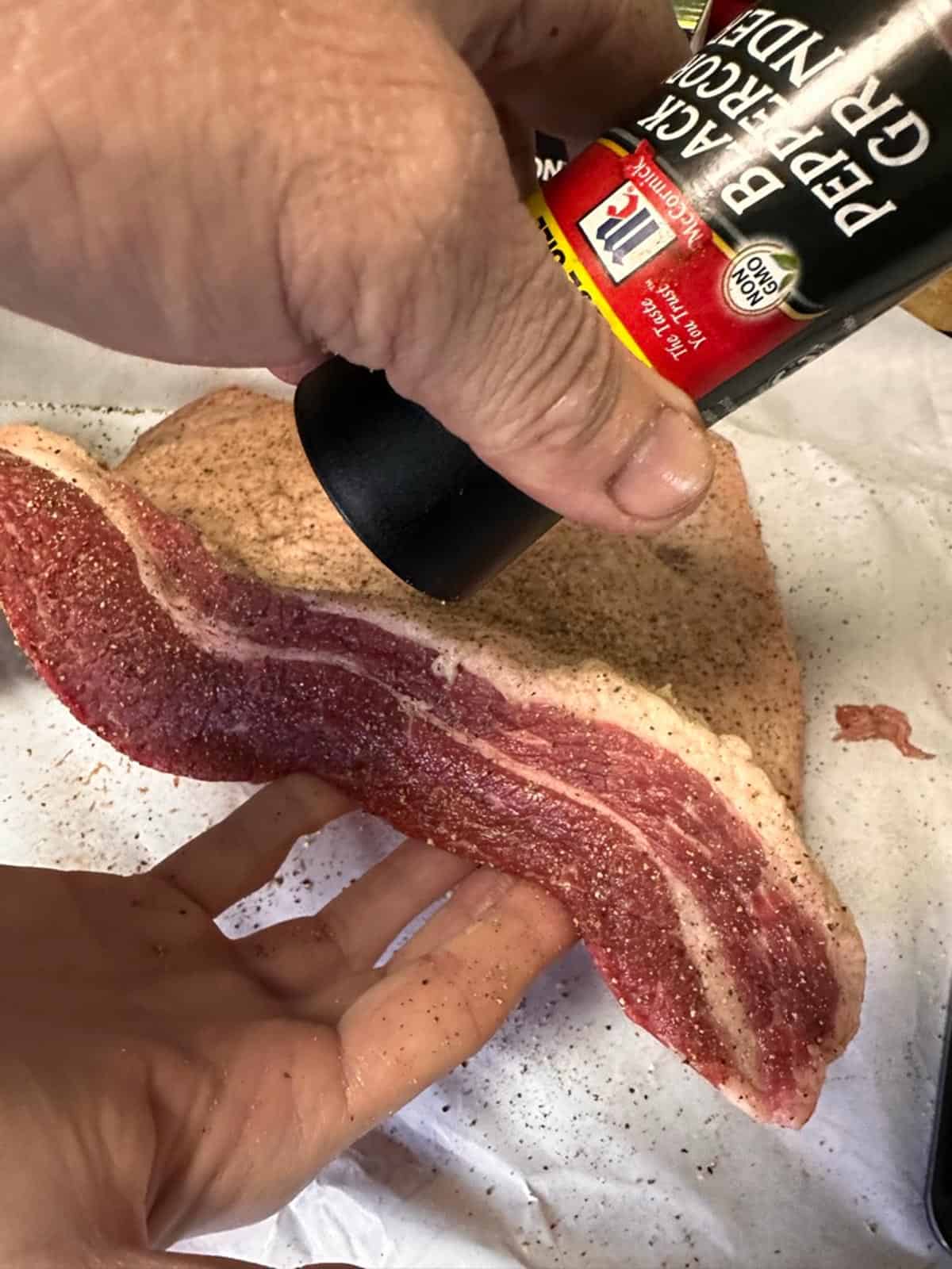 Seasoning a raw brisket.