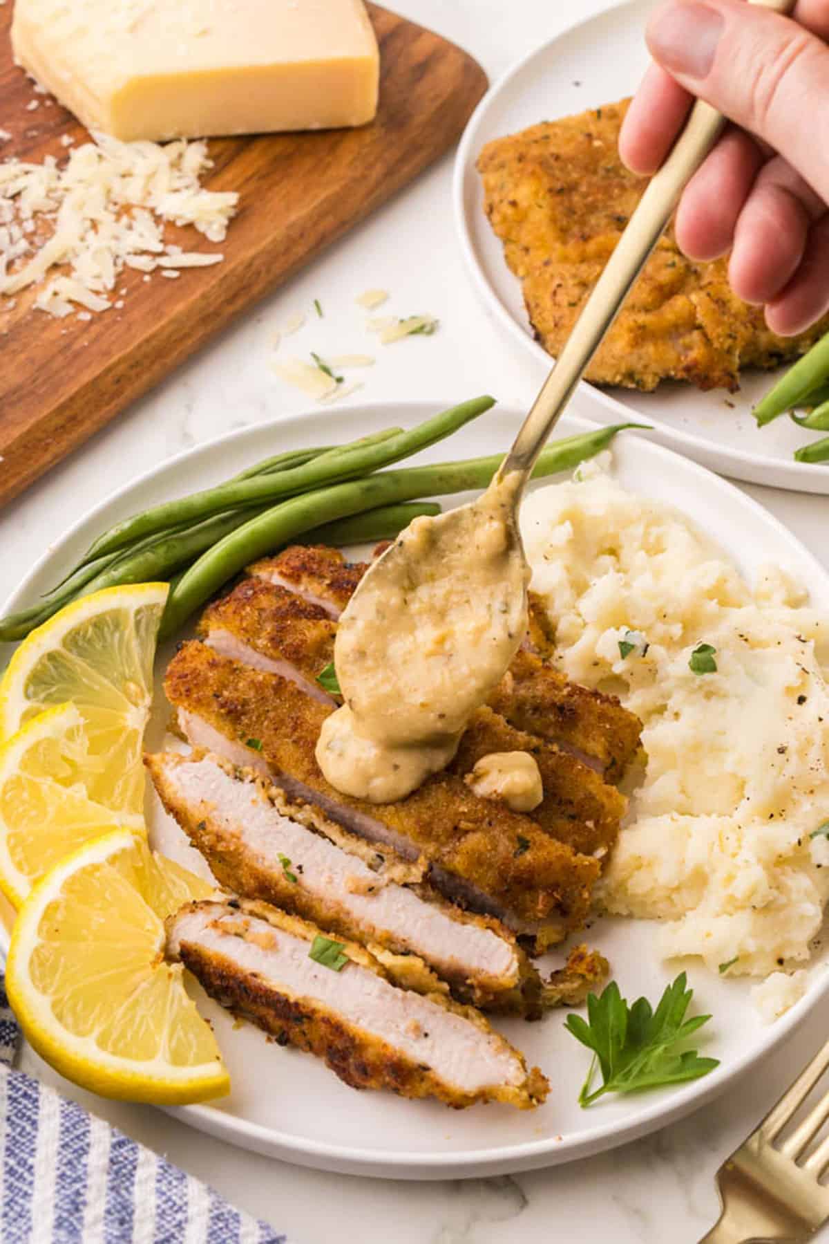 Topping a pork chop with a spoon of sauce.