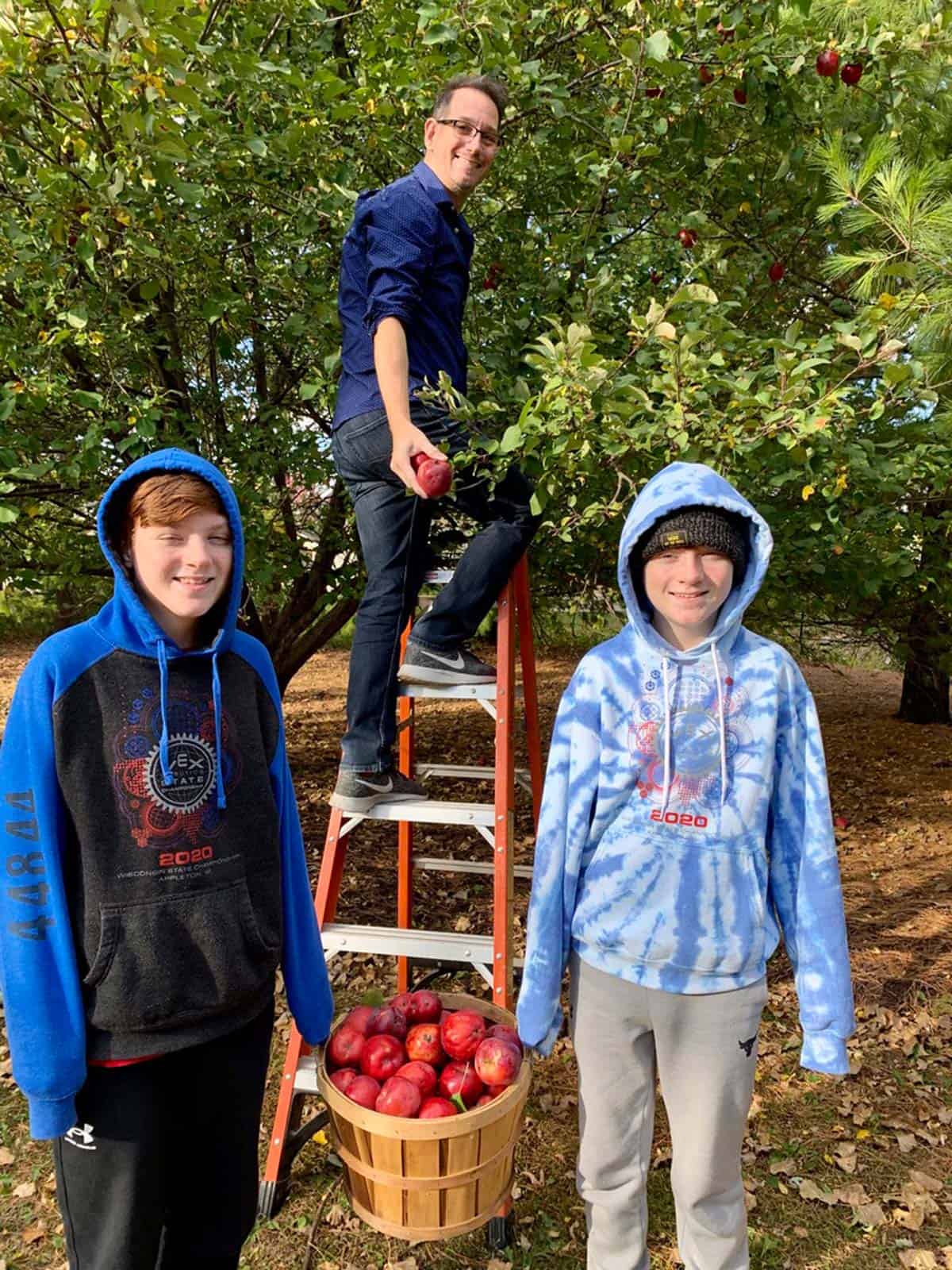 Two boys and their dad picking apples.