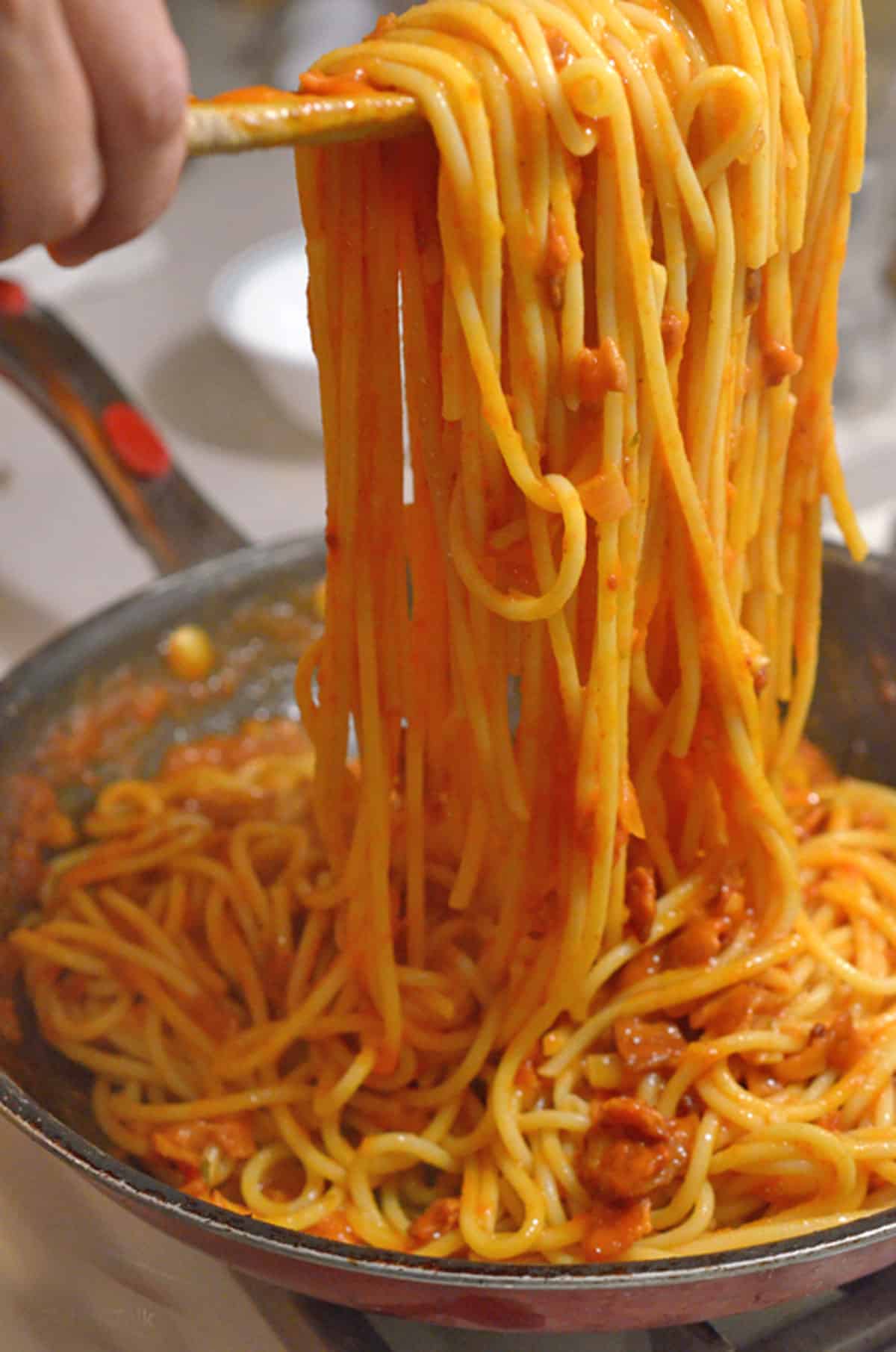 A big spoon of spaghetti in a pot.