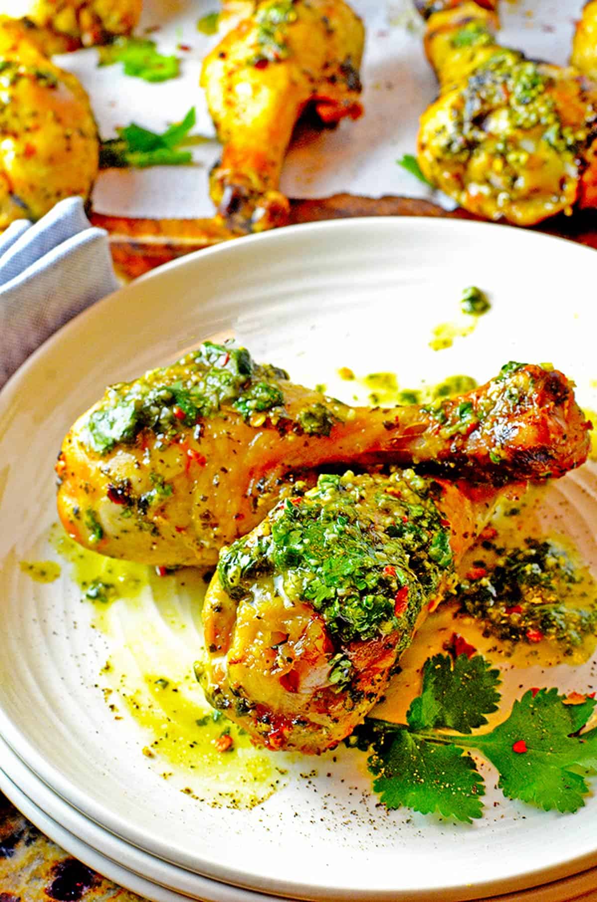 Some chicken drumsticks with chimichurri sauce, on a plate.