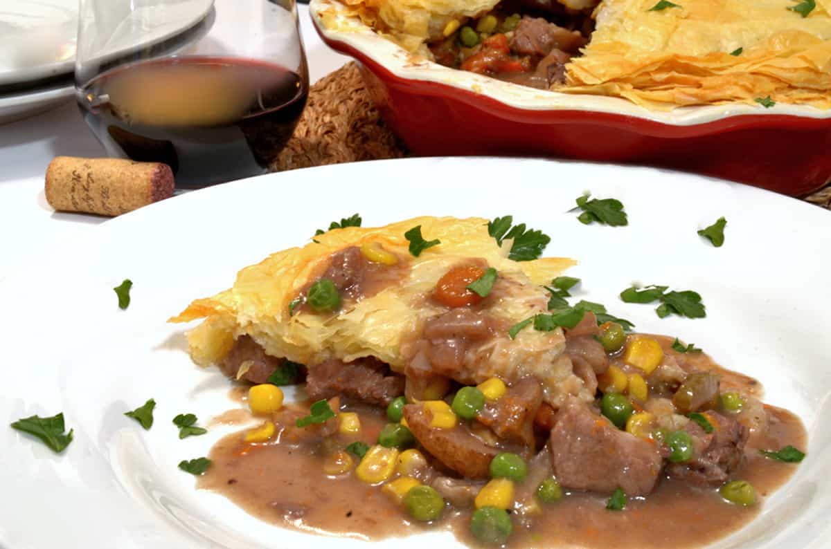 A plate with a slice of beef pot pie on it.