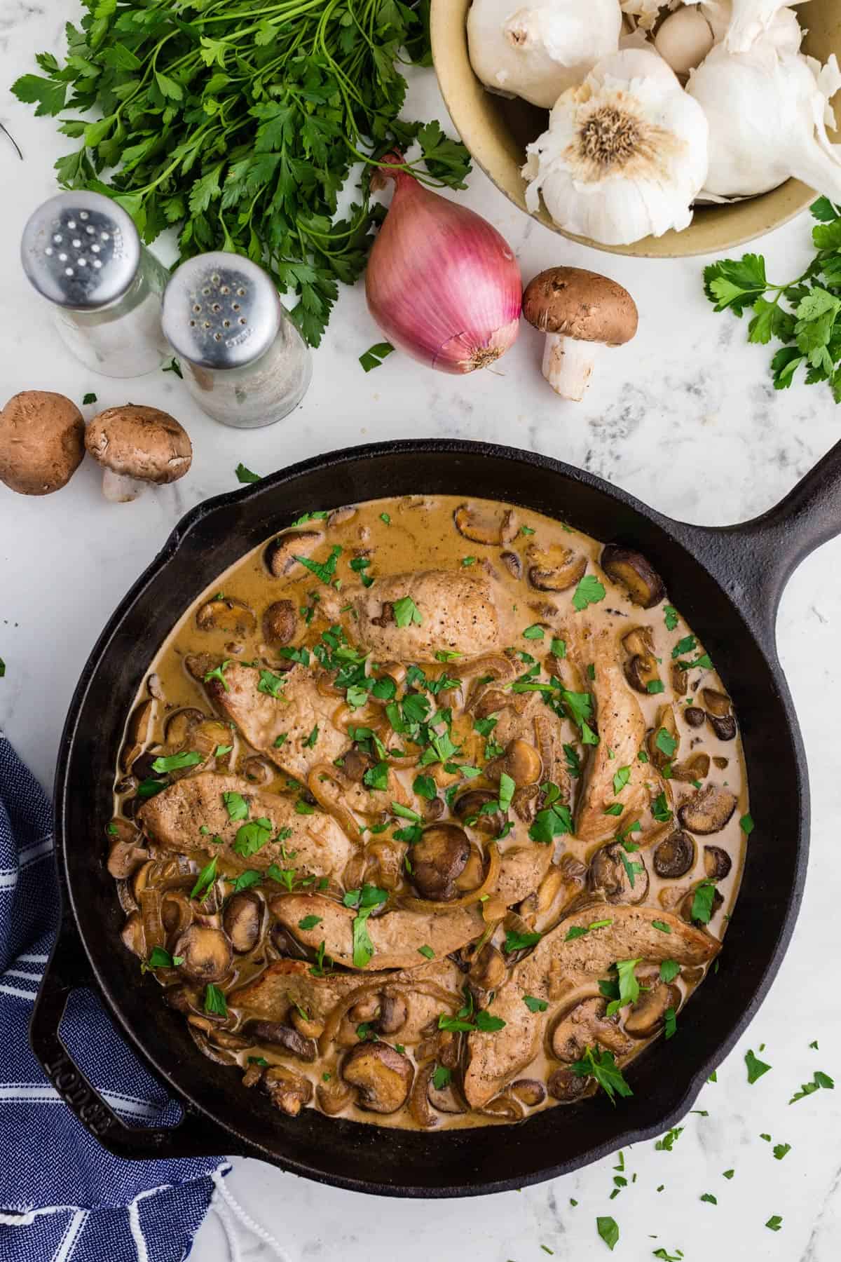 A skillet with veal Marsala with a garnish of chopped parsley.