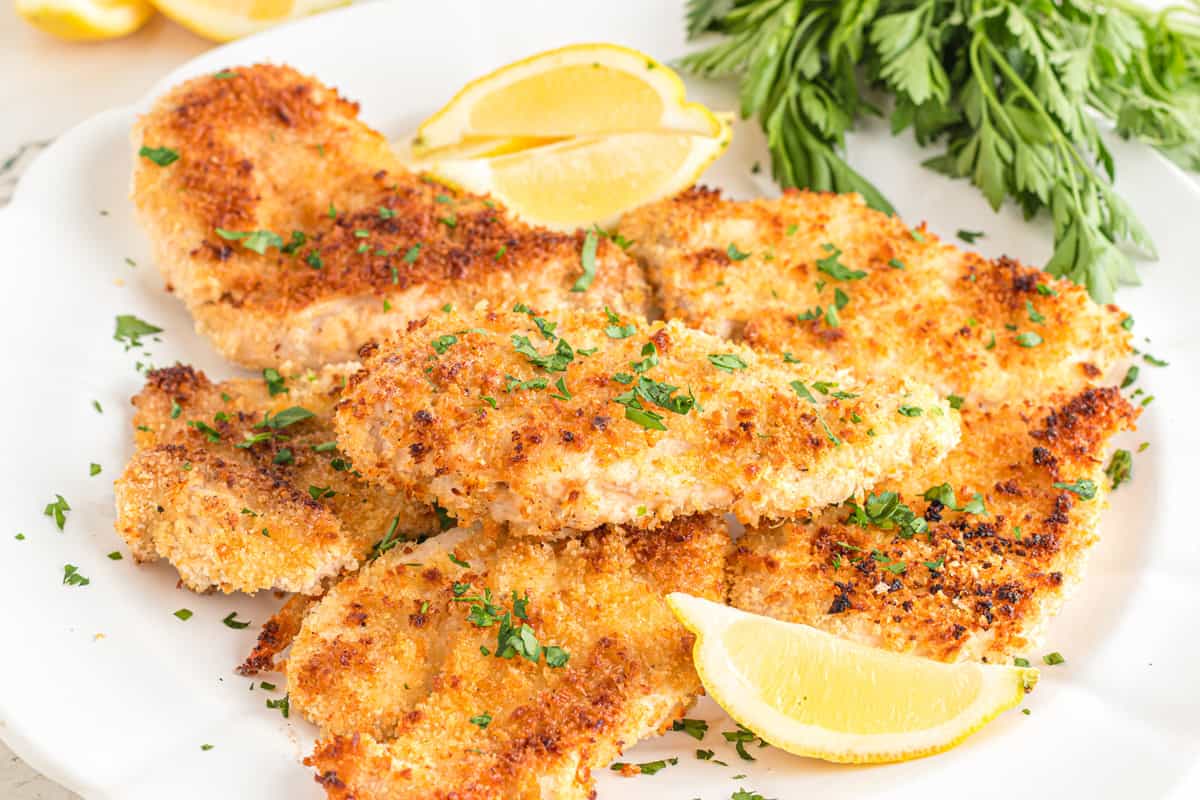 A plate of panko chicken with a lemon wedge and parseley garnish.