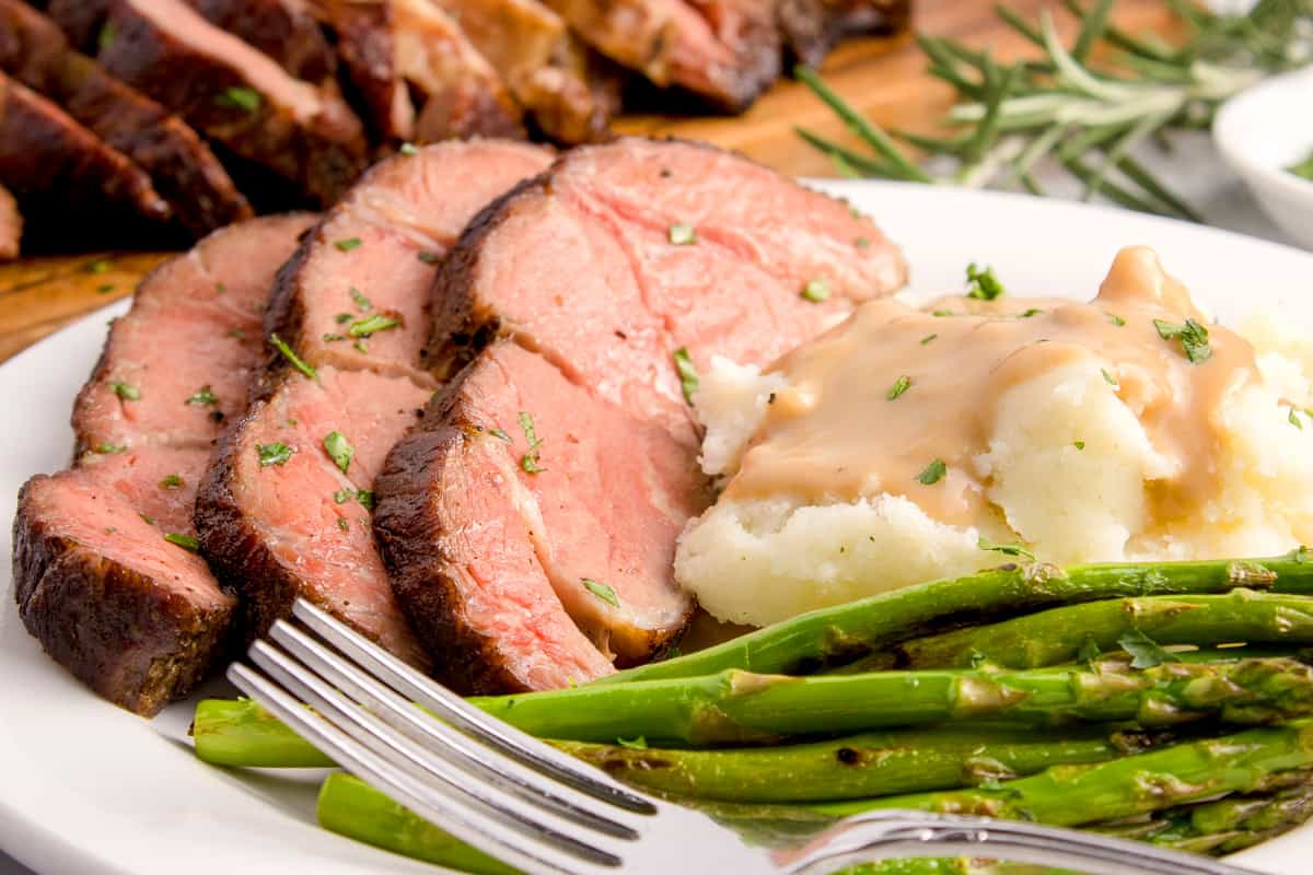 A plate of beef with mashed potatoes and green beans.