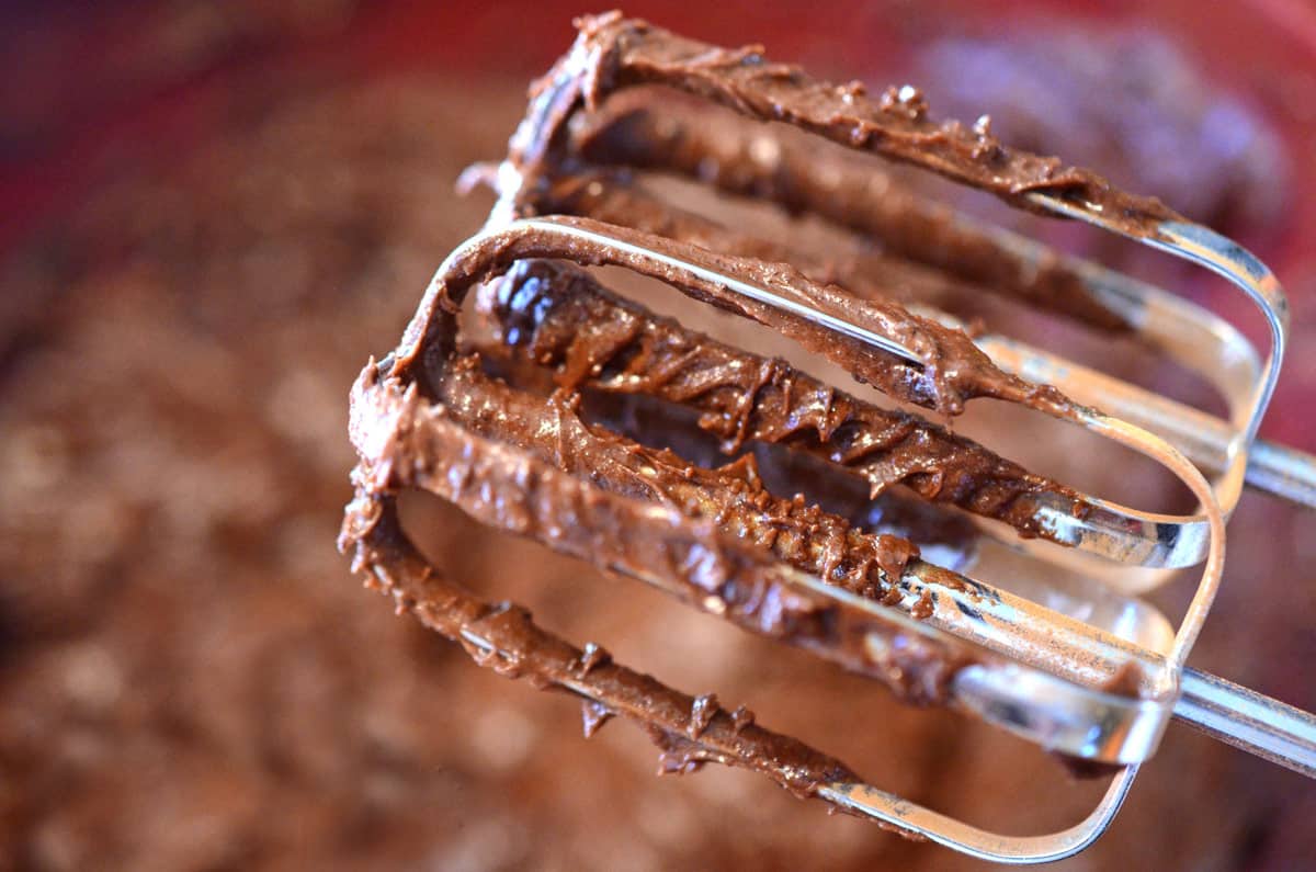 Hand-held electric mixer beaters with chocolate on them.