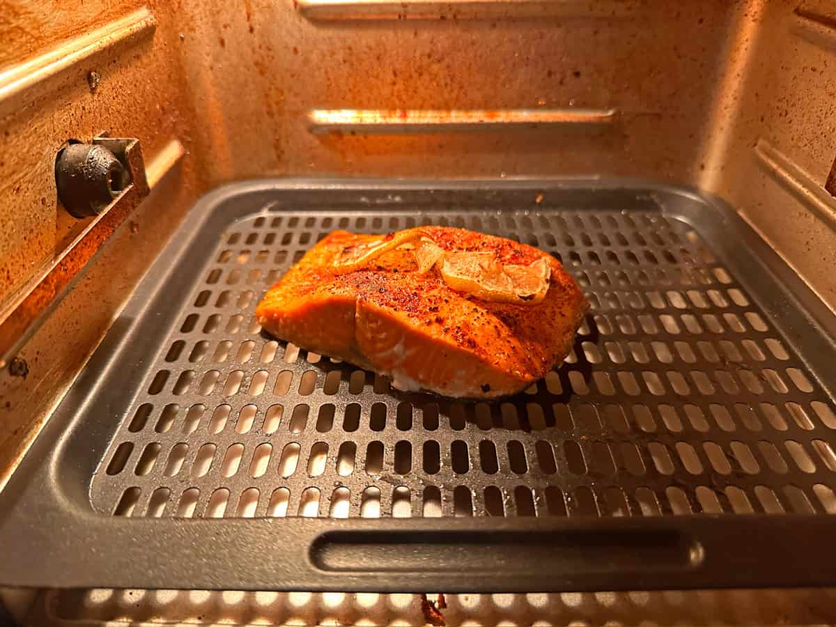 A piece of salmon on an air fryer rack.