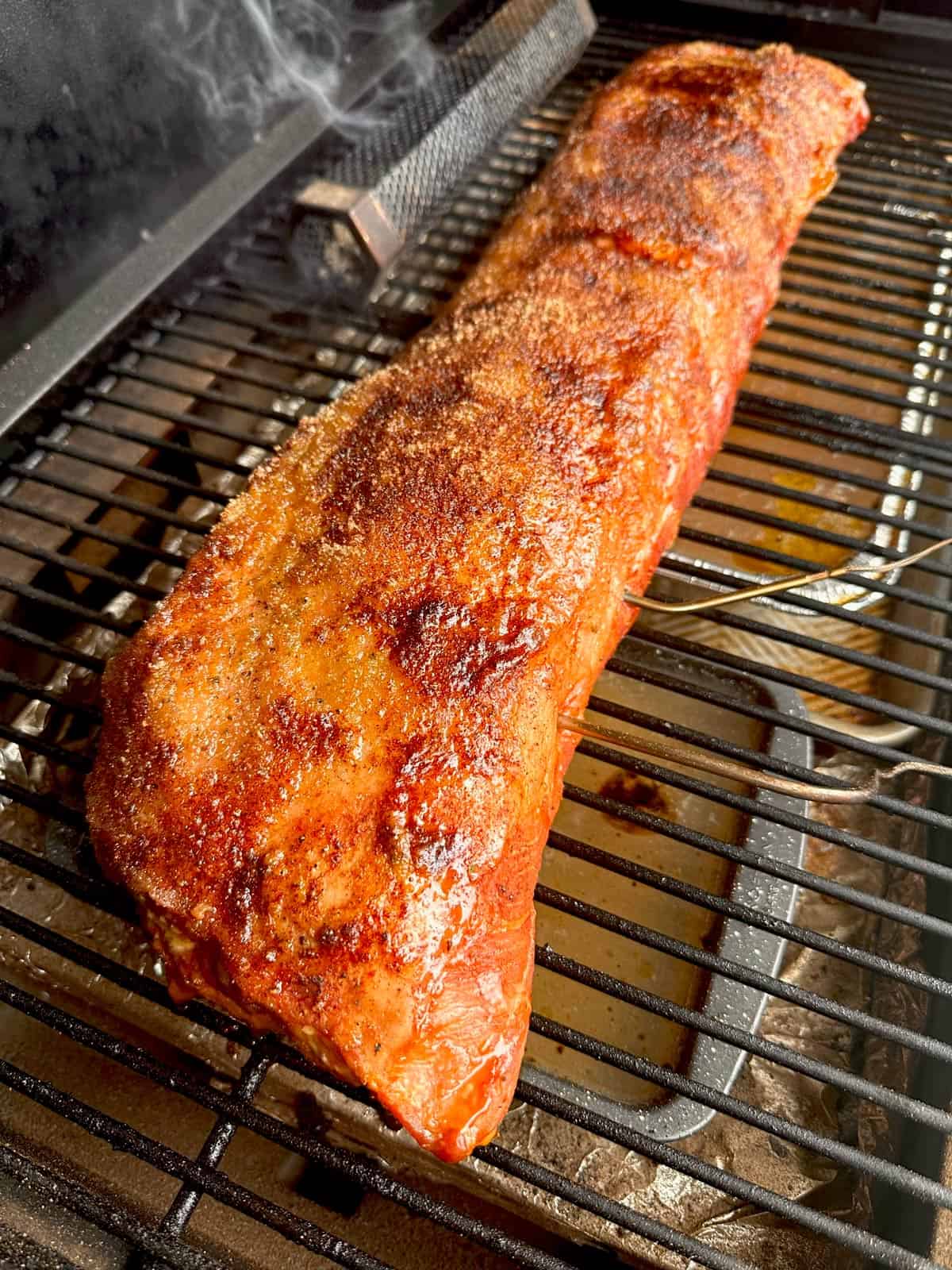 A long piece of golden-brown meat on the grill.