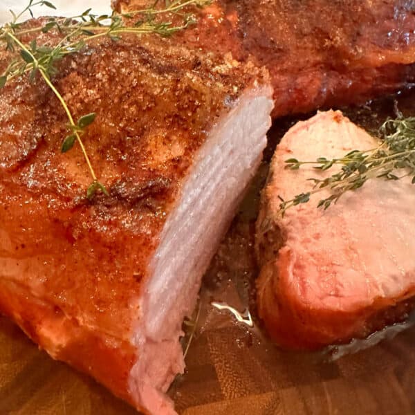 Some juicy pork loin that is sliced, on a cutting board.