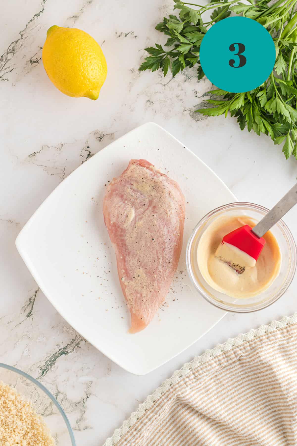 Slathering a raw chicken breast with some mayonnaise.