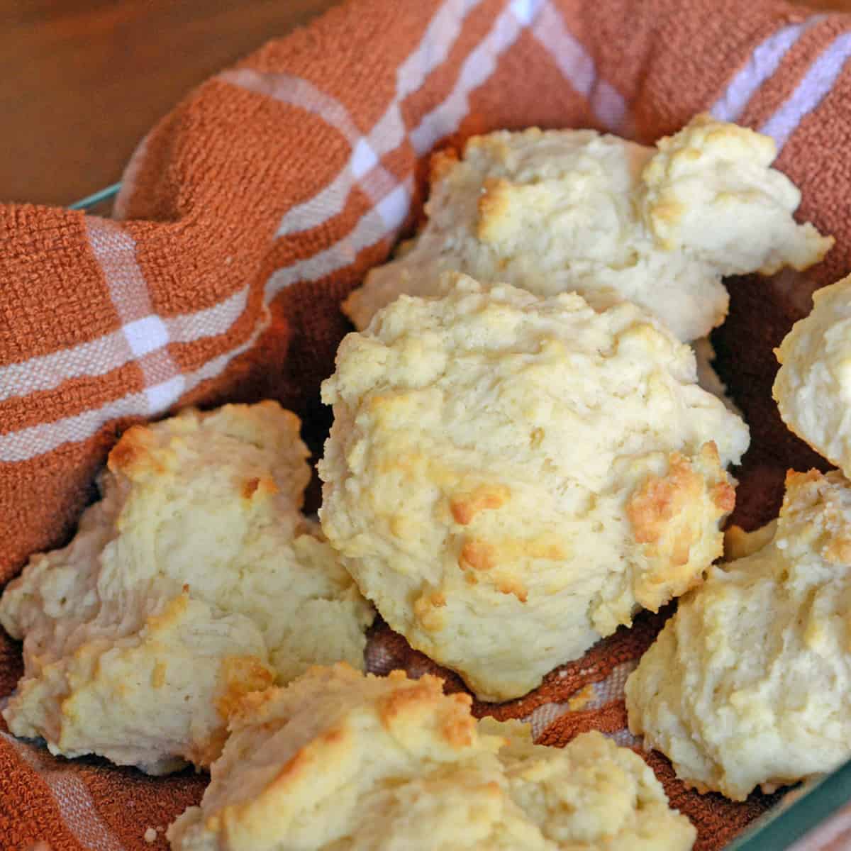 A basket of fresh biscuits on a kitchen towel.