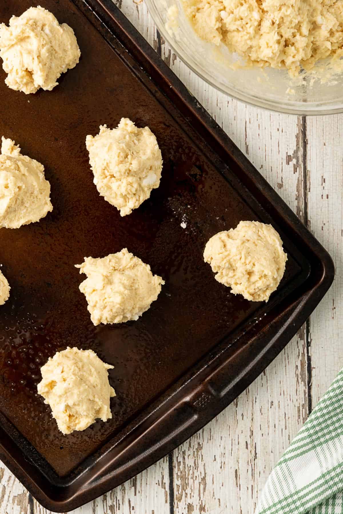 Some unbaked biscuits on a cookie sheet.