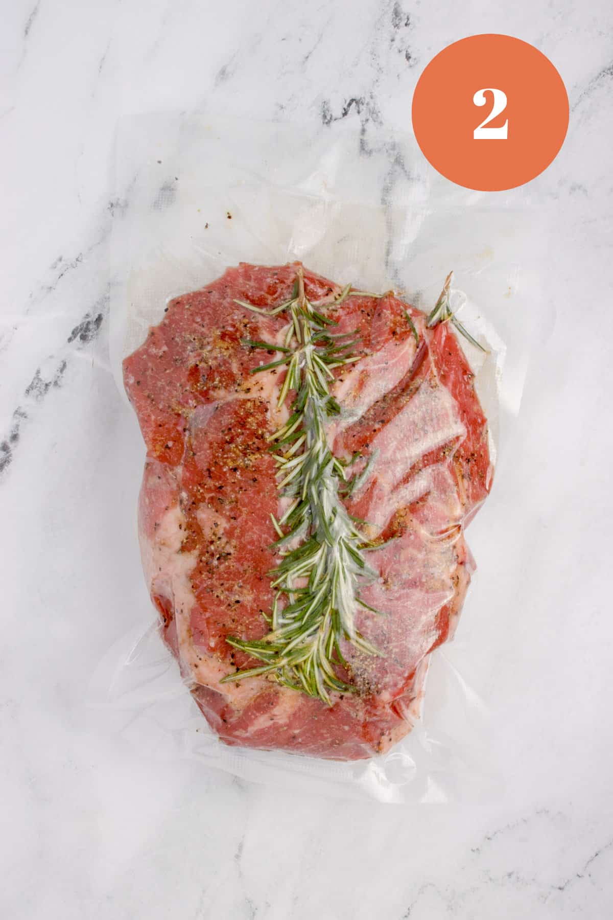 A hunk of chuck roast with a rosemary sprig inside of a sous vide bag.