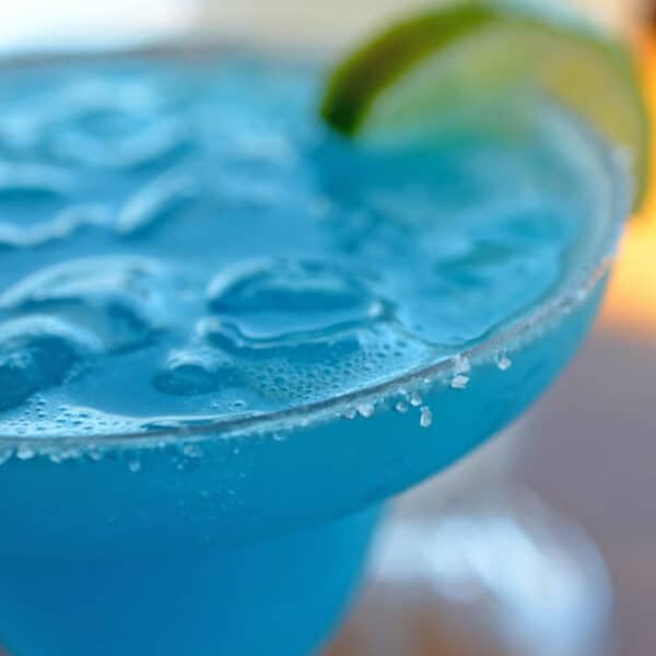 A blue drink with ice and a lime garnish.