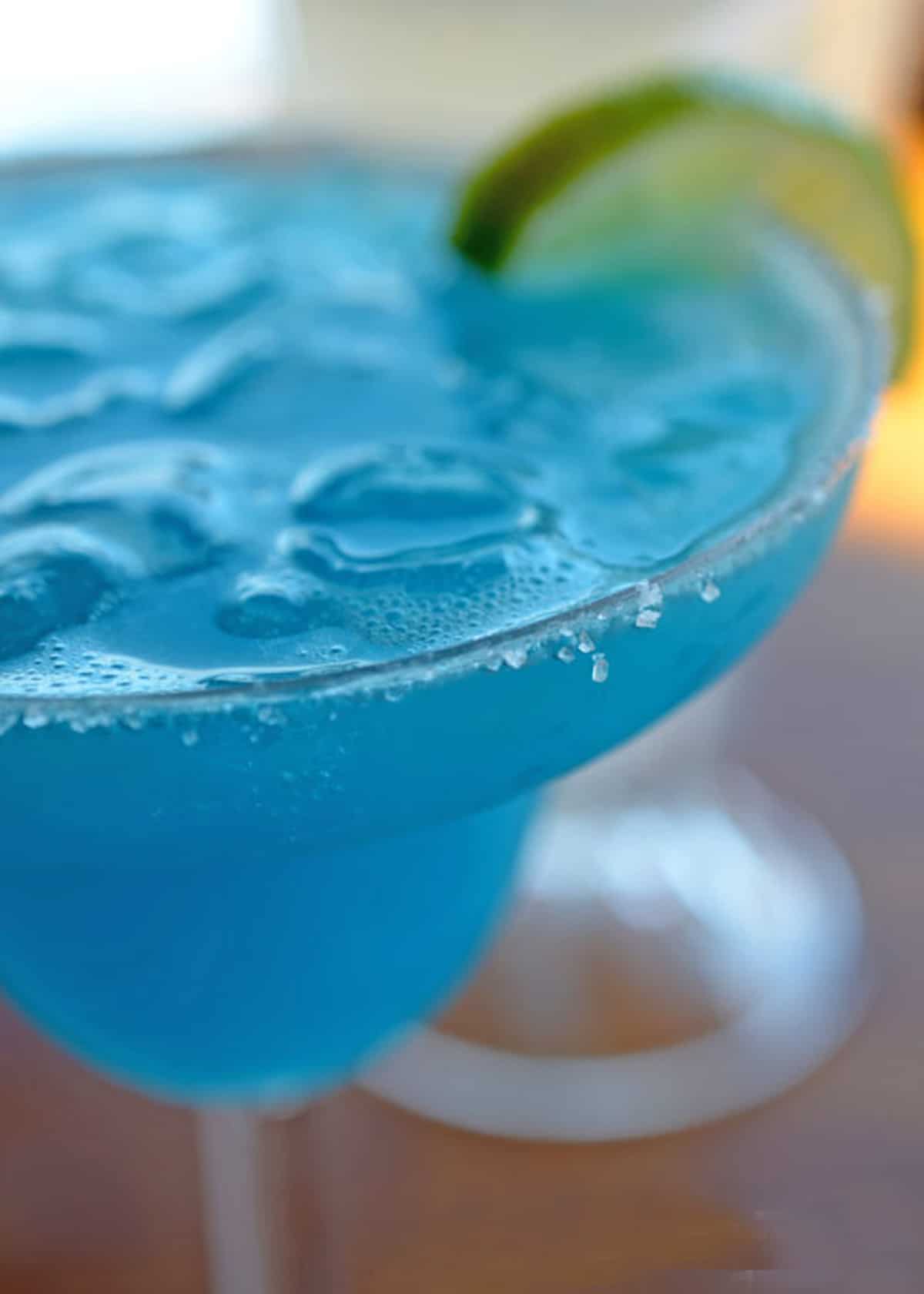 A blue margarita with lime on the rim.
