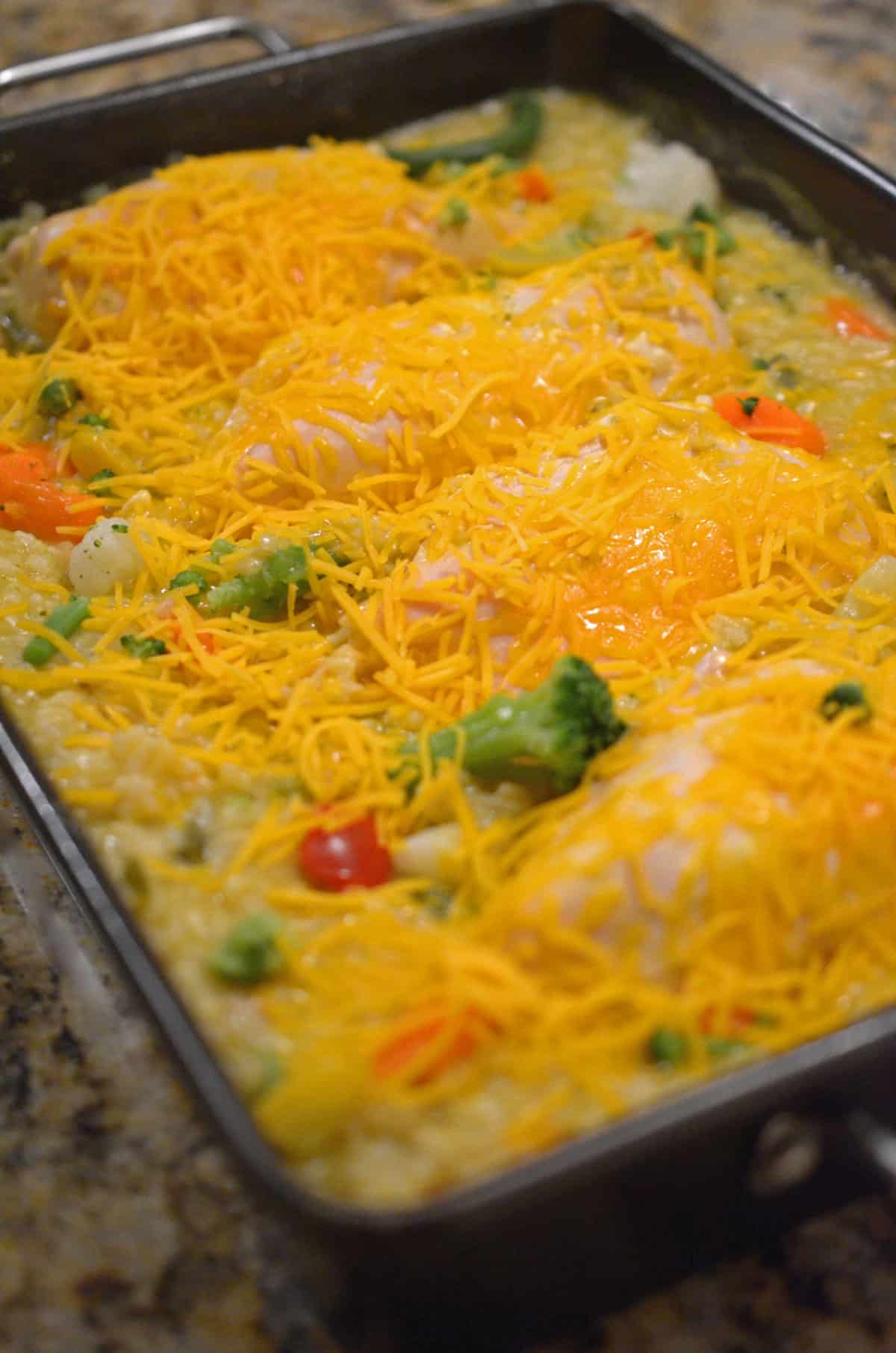 A casserole pan full of chicken and rice, covered in cheese.
