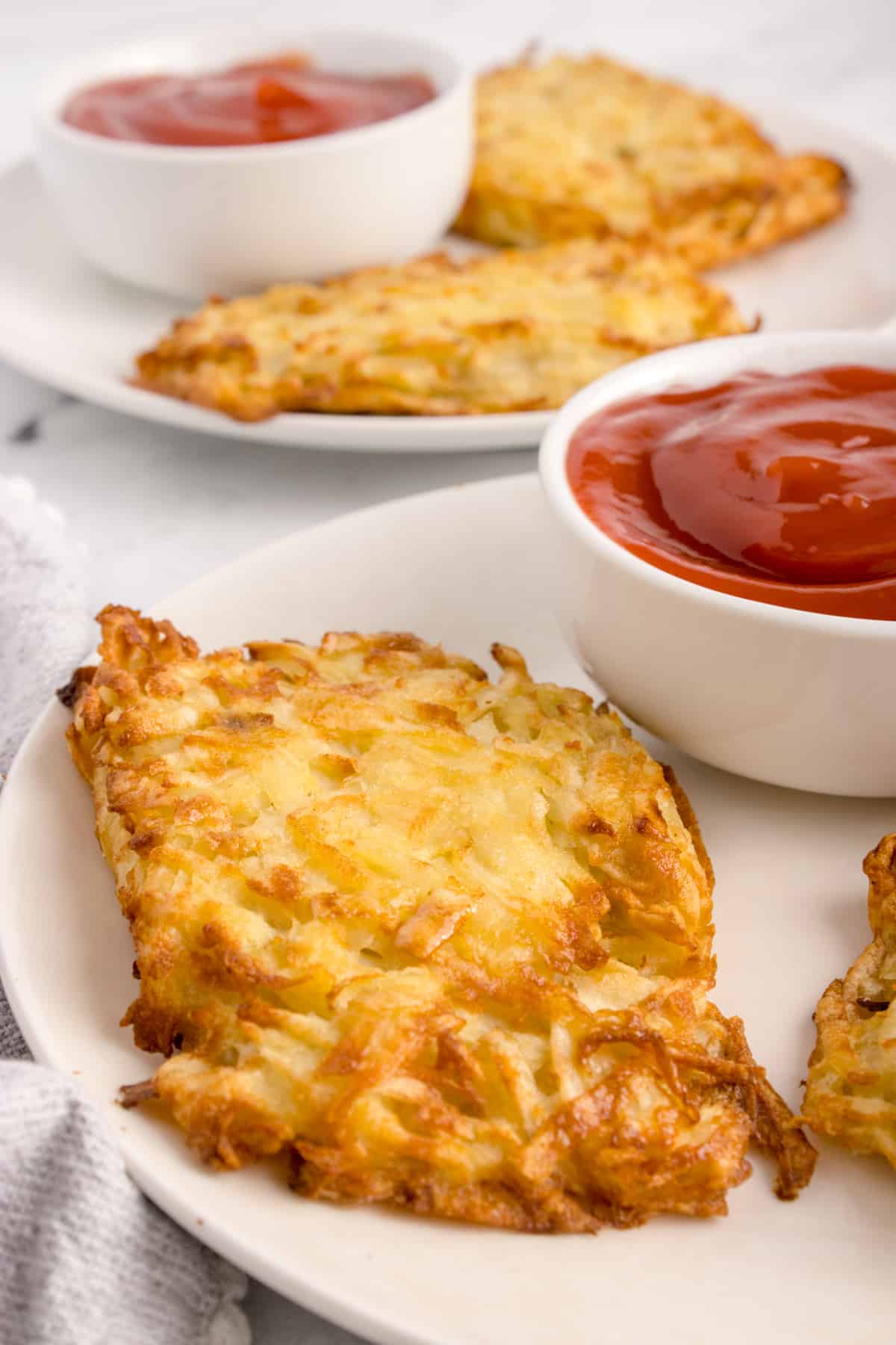 Some hash browns and ketchup on a plate.