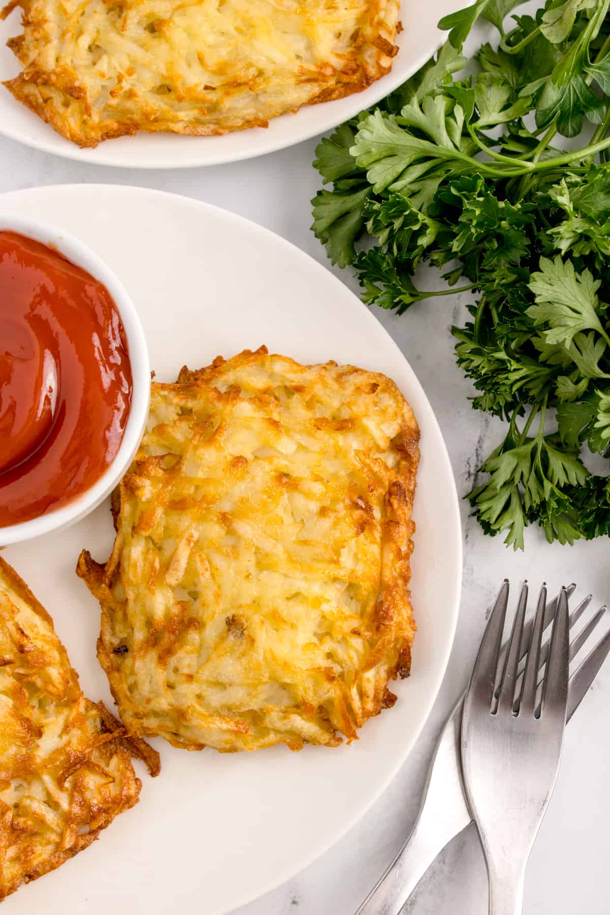 Some hash browns on a plate with a garnish of Italian parsley.