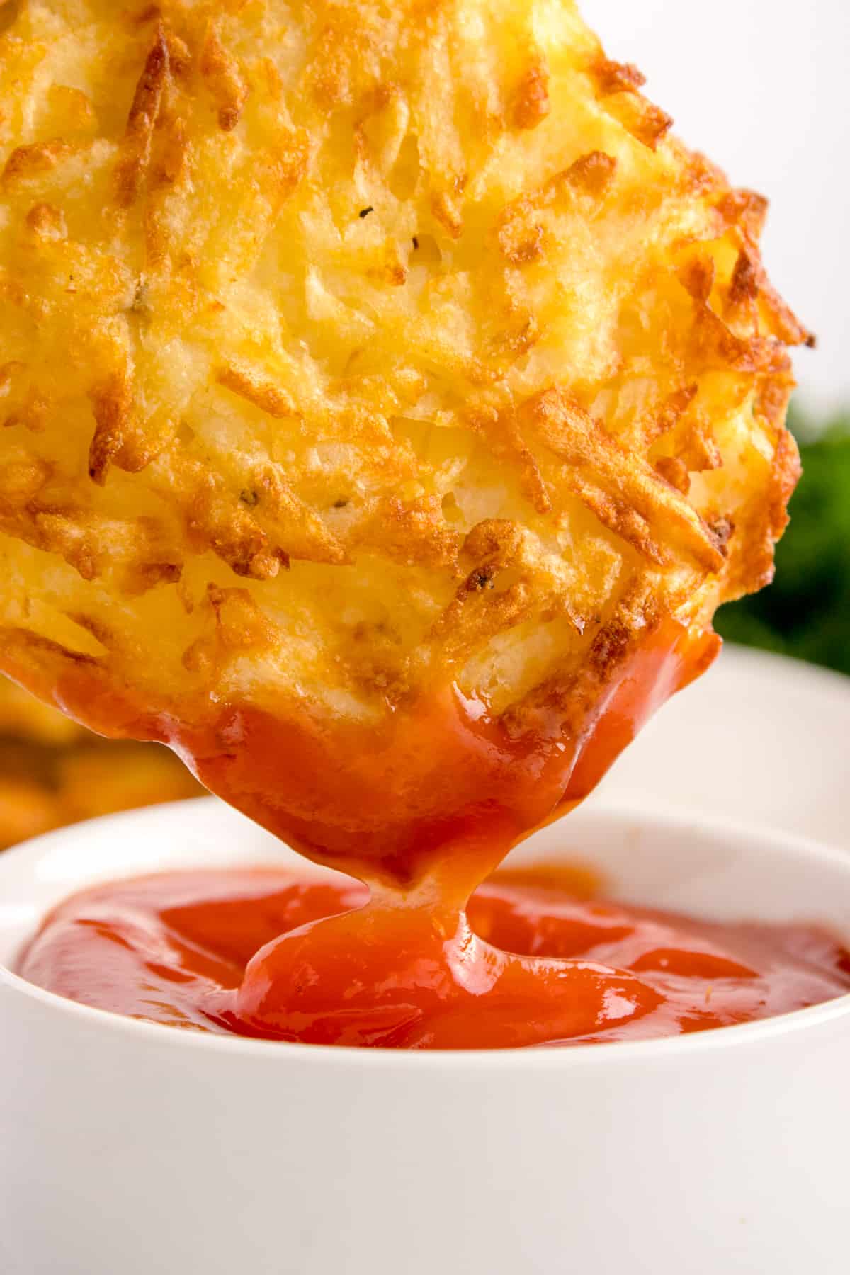 Dipping a hash browns pattie into a dish of ketchup.