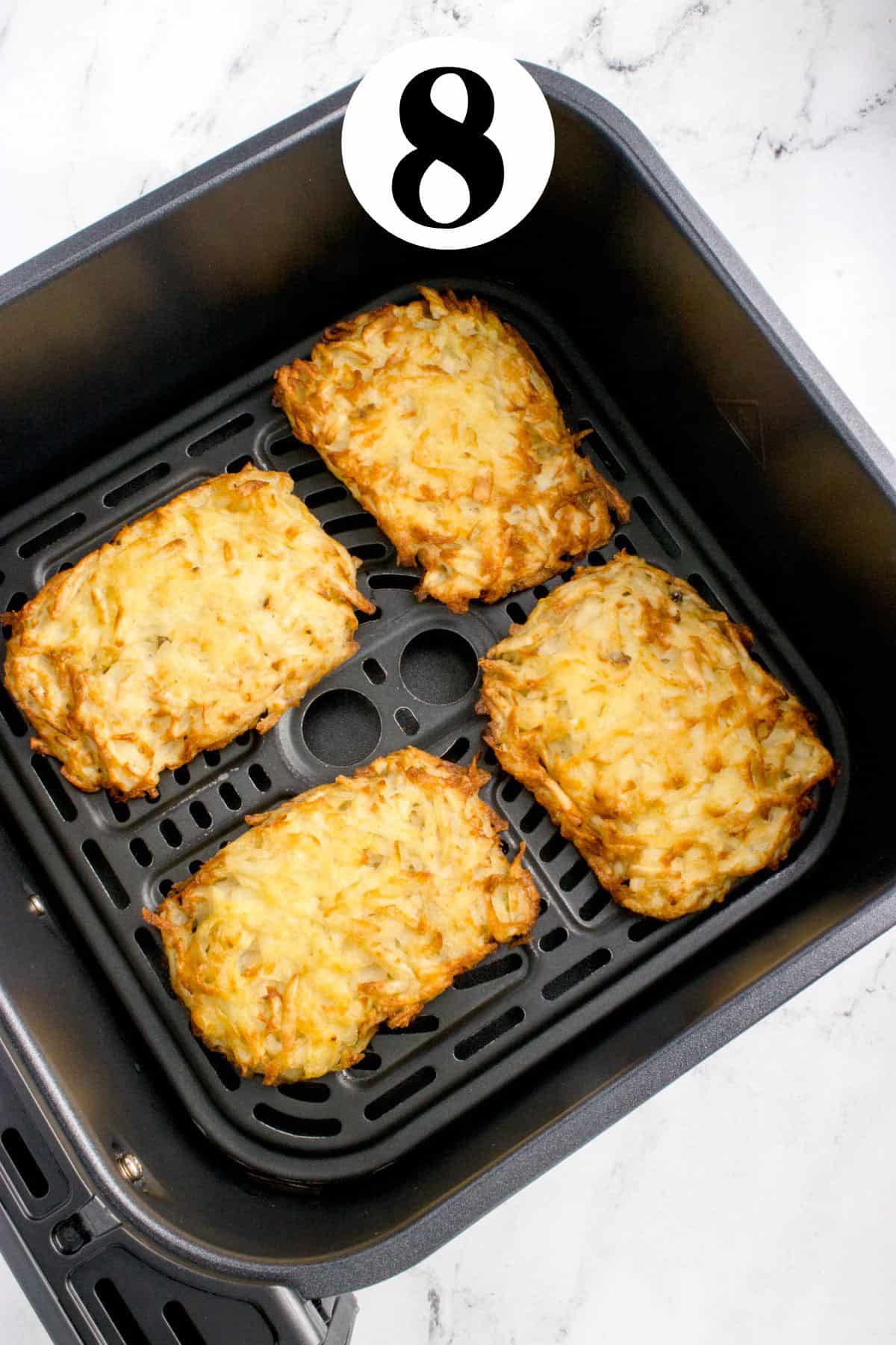 A group of golden brown hash browns in an air fryer basket.