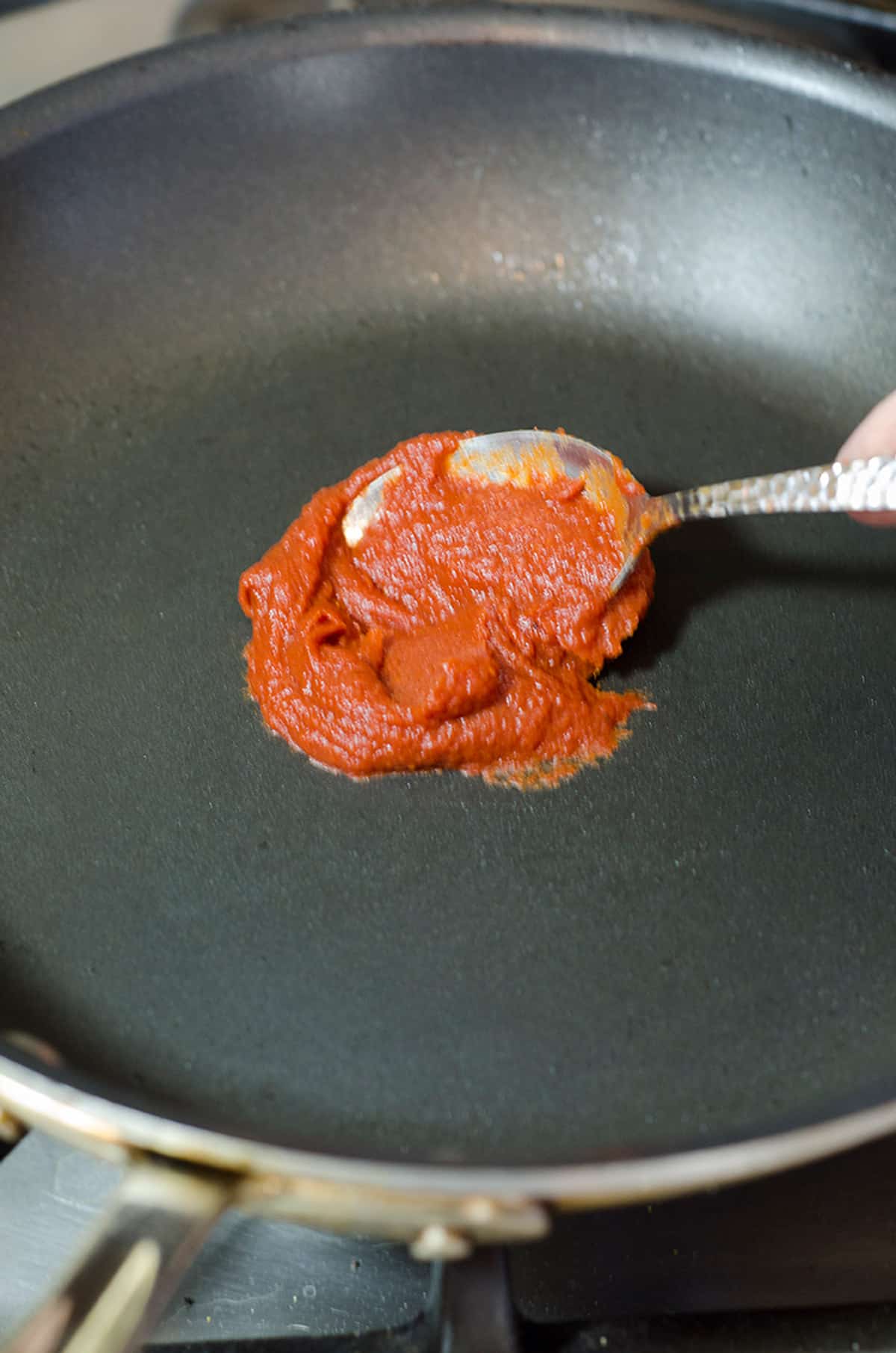 Adding tomato paste to a skillet.