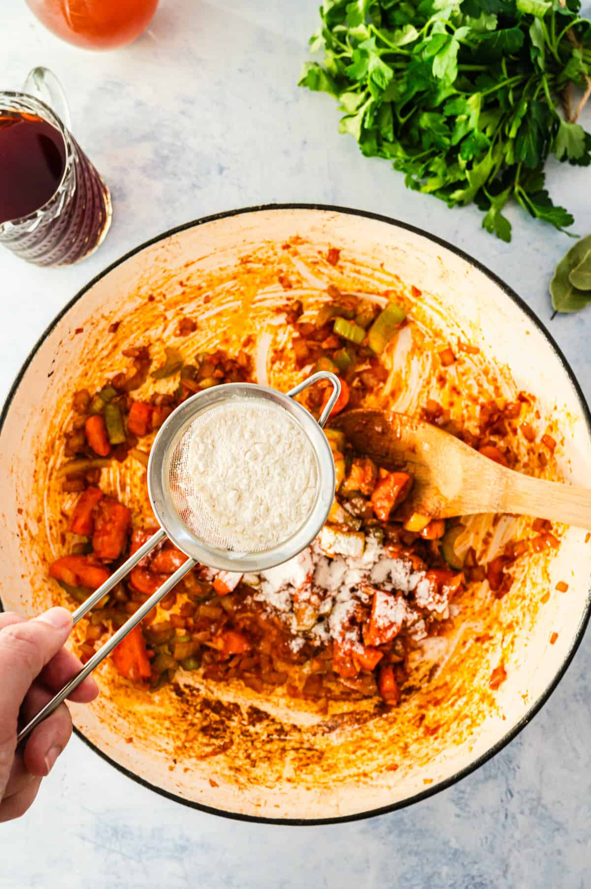 Adding flour to a pot of vegetables.