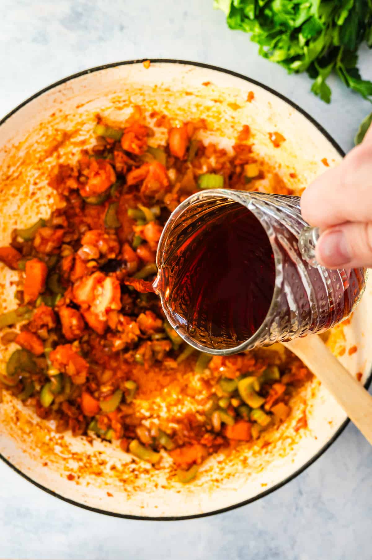 Pouring red wine into a bot of vegetables.