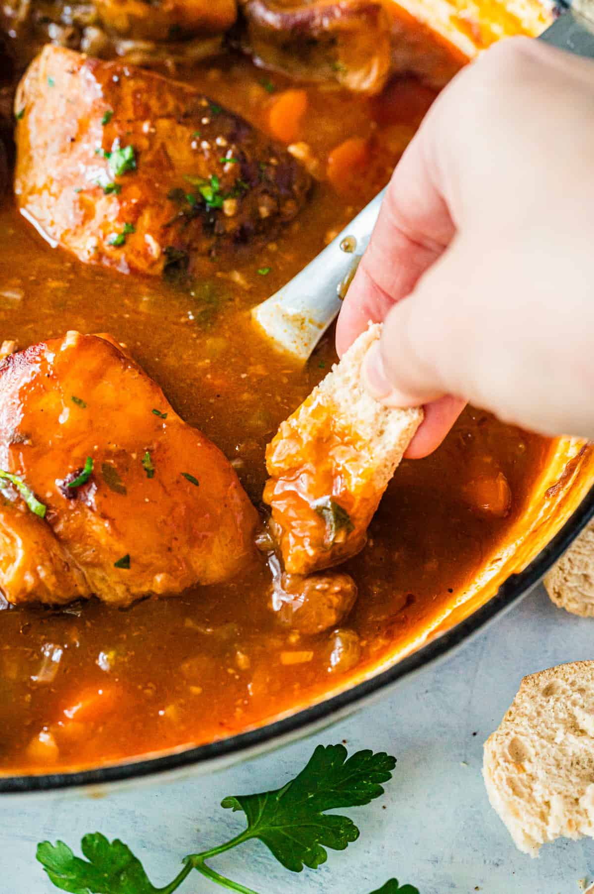 Dipping some crusty bread. into a pot of braised beef.