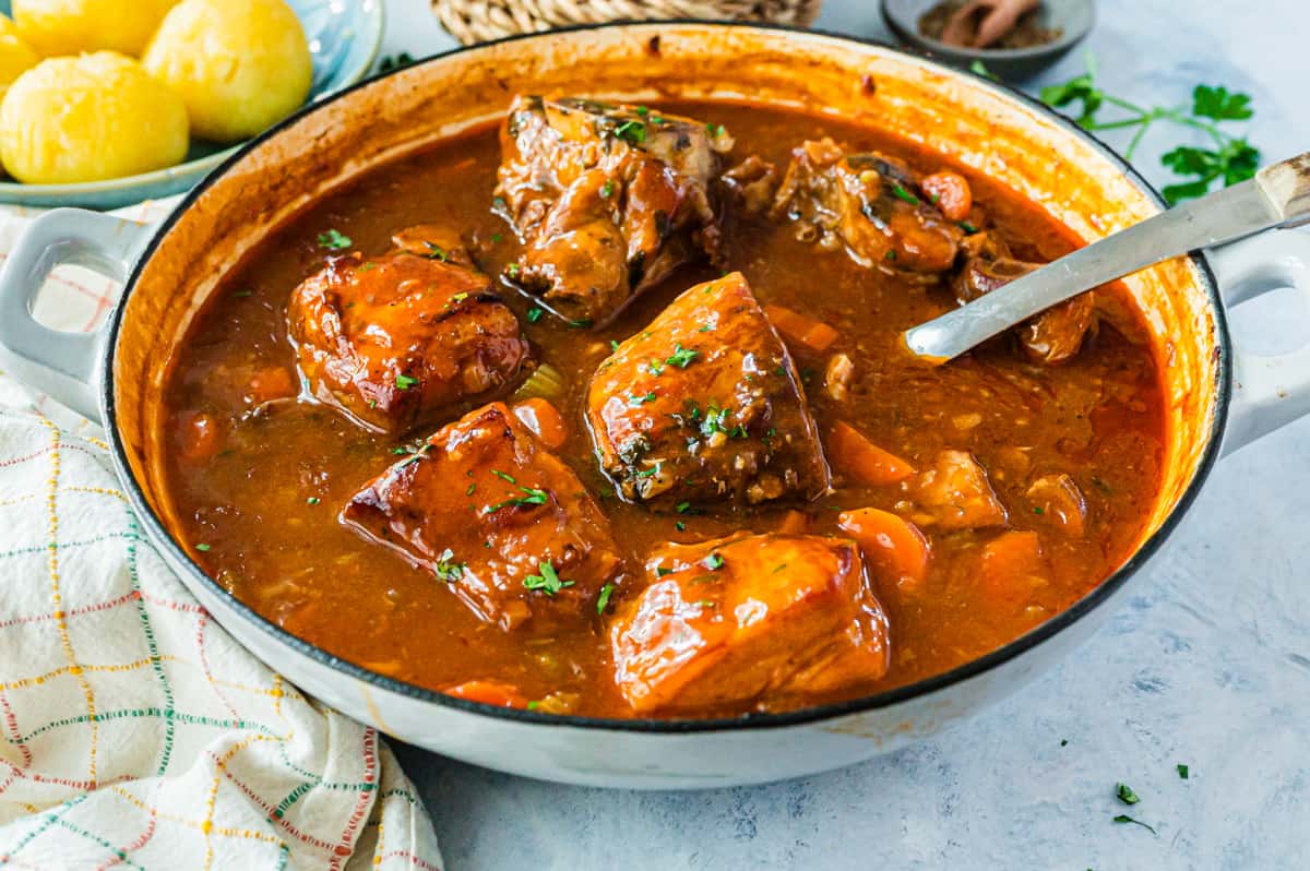 A pot of braised beef garnished with parsley.