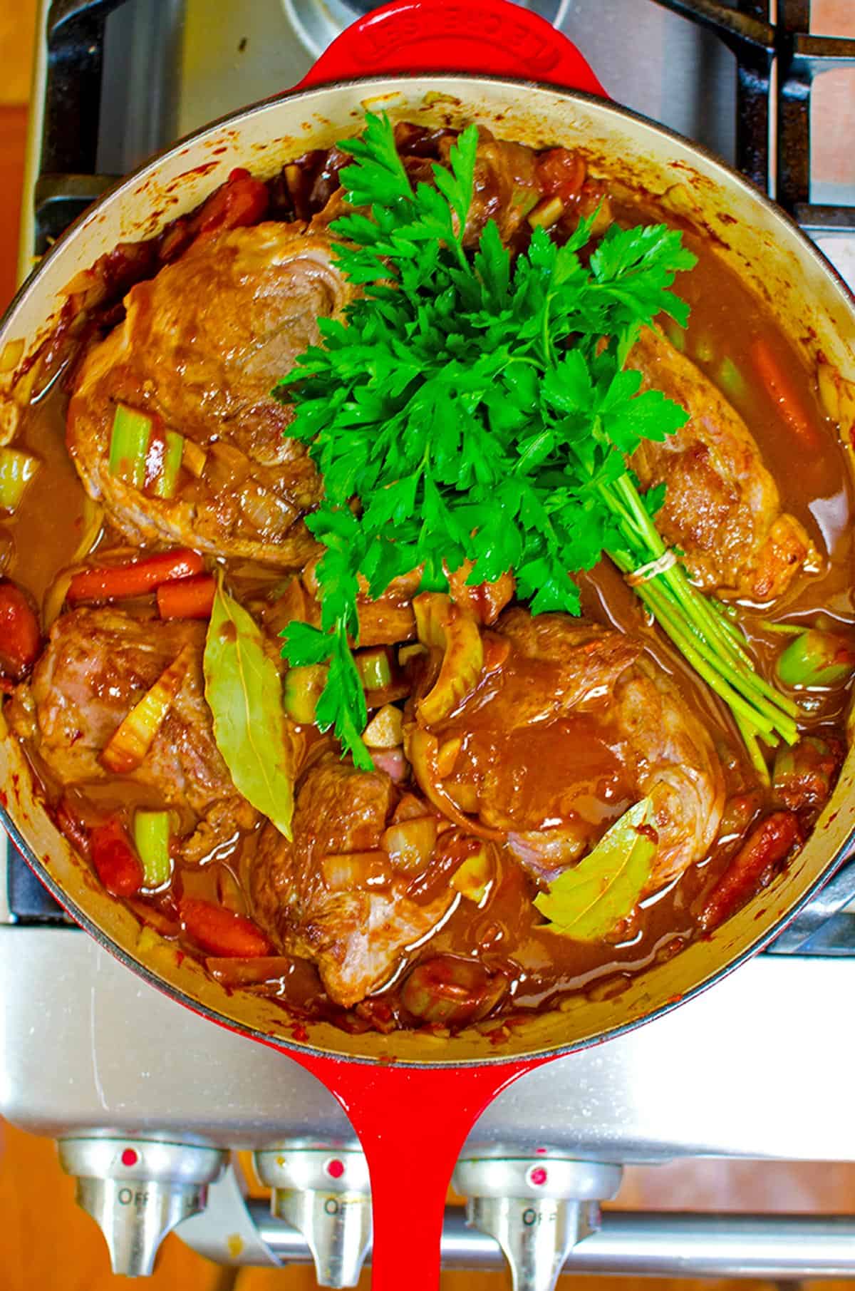 A pot of meat with a bunch of parsley on it.