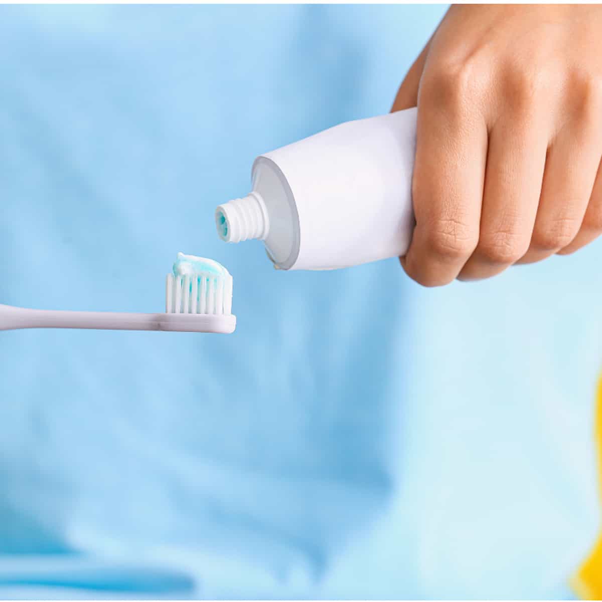 Squeezing some toothpaste onto a toothbrush.