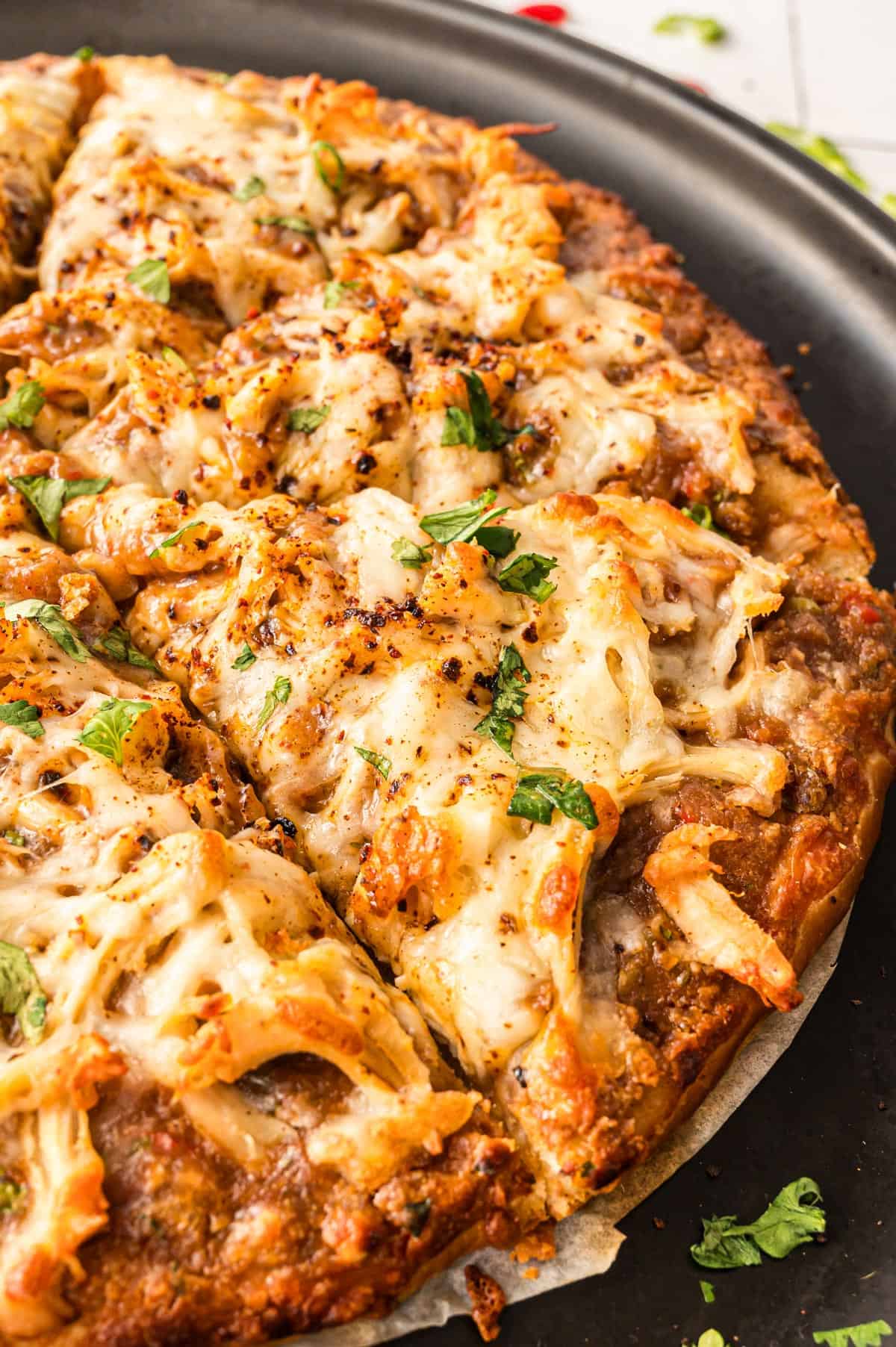A pan of cheesy pizza with green garnish.