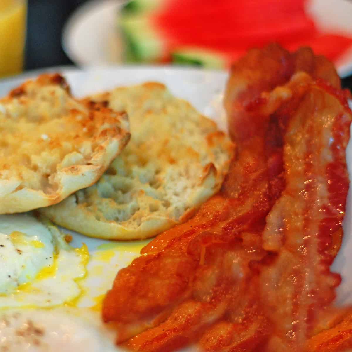 A plate of bacon, eggs, and English muffins.