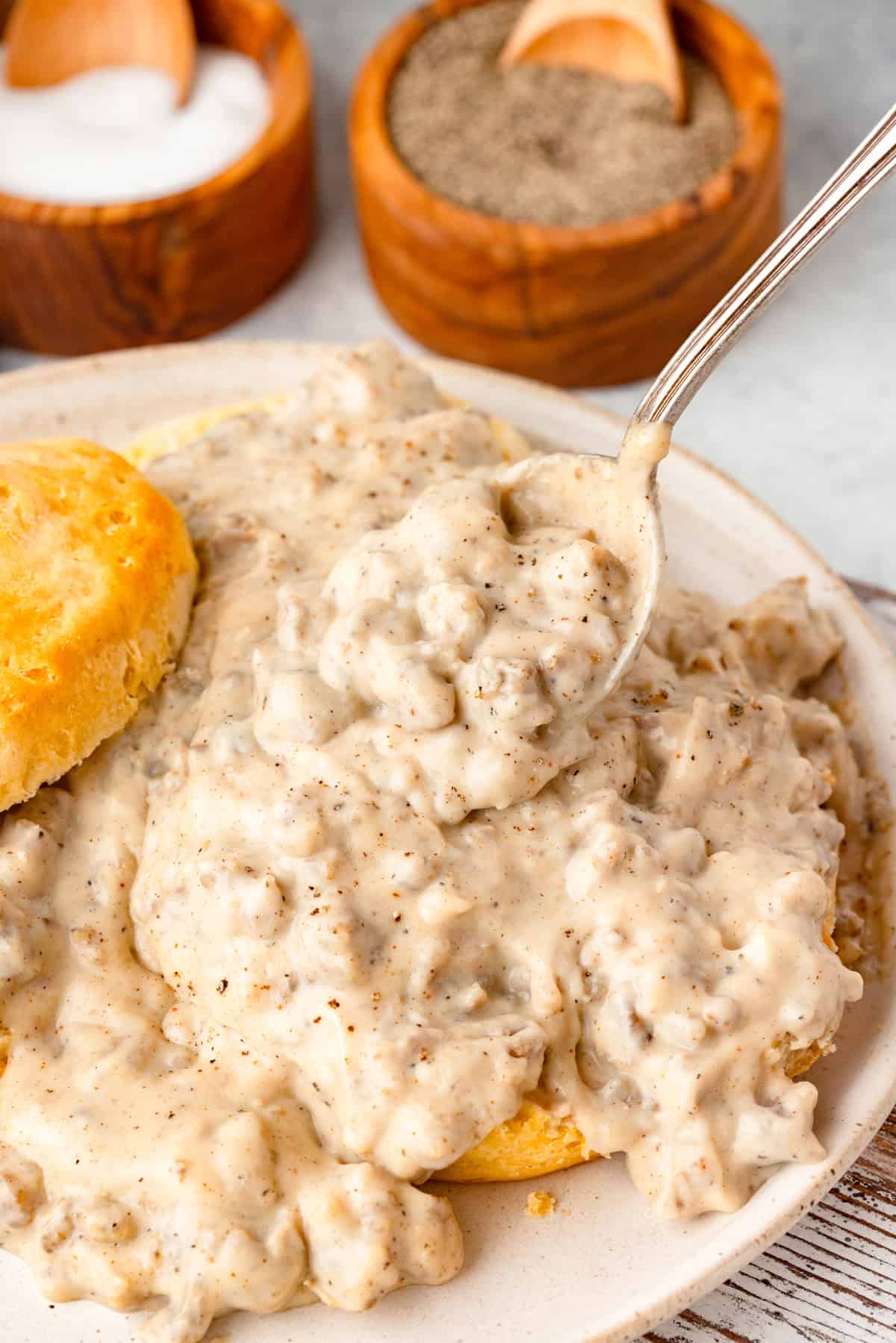 A plate of sausage gravy being spooned up.