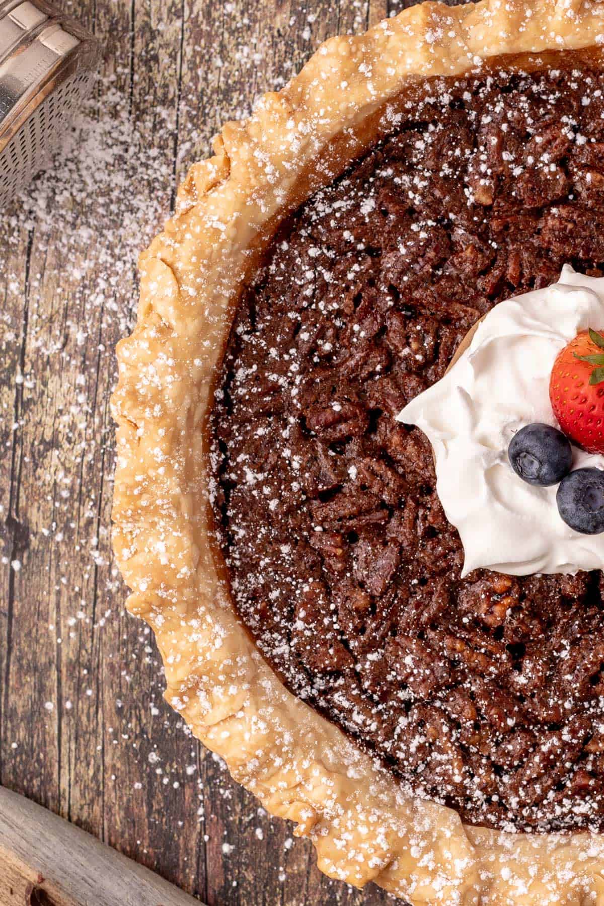 A chocolate pie with a dollop of whipped cream and berries on top.