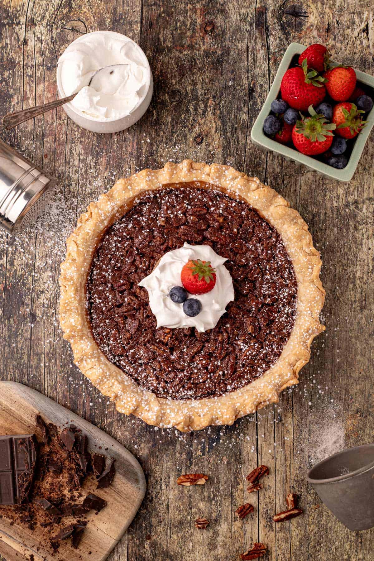 A chocolate chess pie with whipped cream and berries in the center.