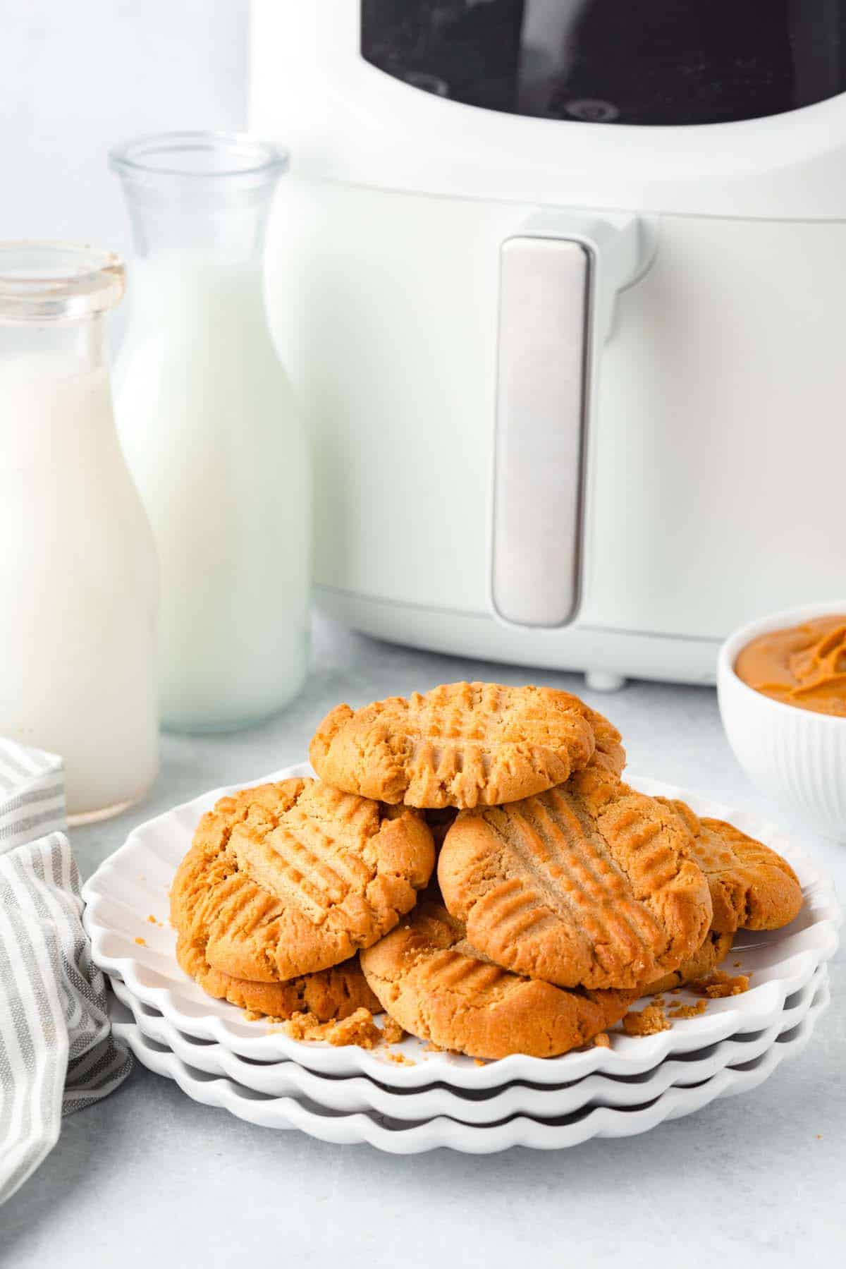 A plate of peanut butter cookies in front of an air fryer.