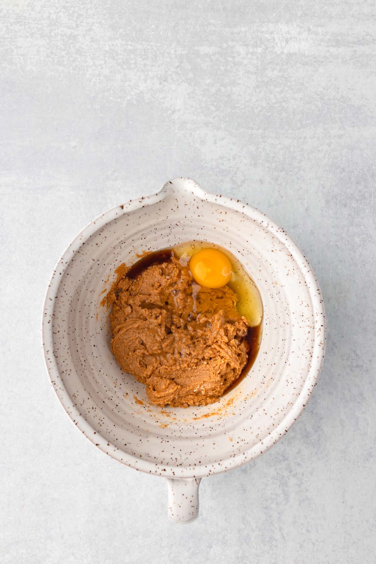 Some peanut butter, egg, and vanilla in a mixing bowl.