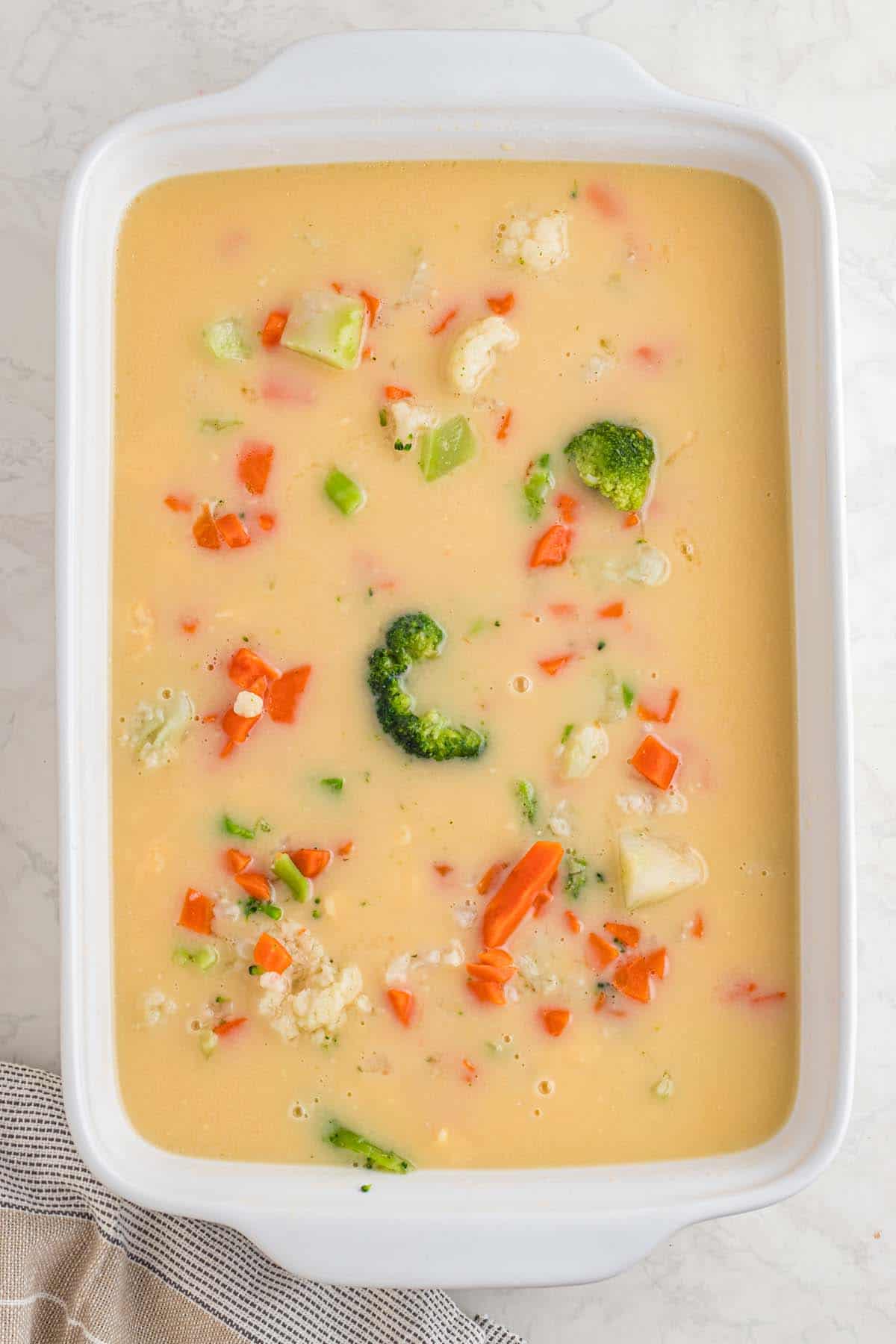 A casserole dish with some vegetables floating in broth.