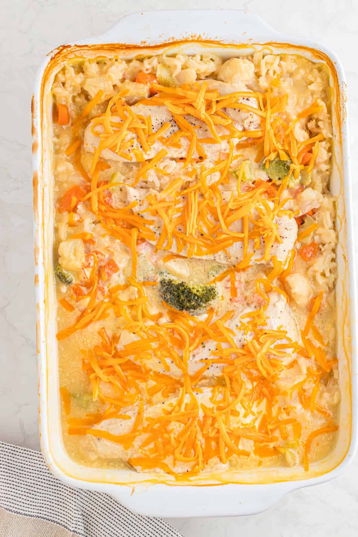 A casserole dish with shredded cheese melted over chicken breasts.
