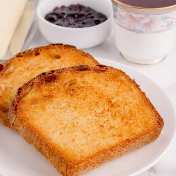 Two slices of golden brown toast with jam and coffee.